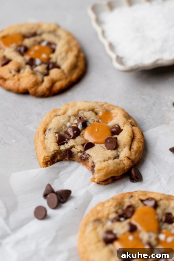 Gooey Caramel Chocolate Chip Cookies 3 A perfectly baked caramel chocolate chip cookie with a bite taken out, revealing its soft, chewy interior and gooey caramel filling.