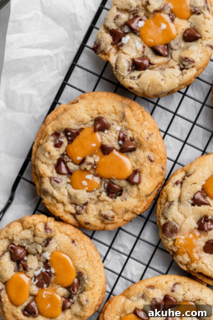 Gooey Caramel Chocolate Chip Cookies 8 Top view of freshly baked caramel chocolate chip cookies on a cooling rack, glistening with melted caramel and chocolate.