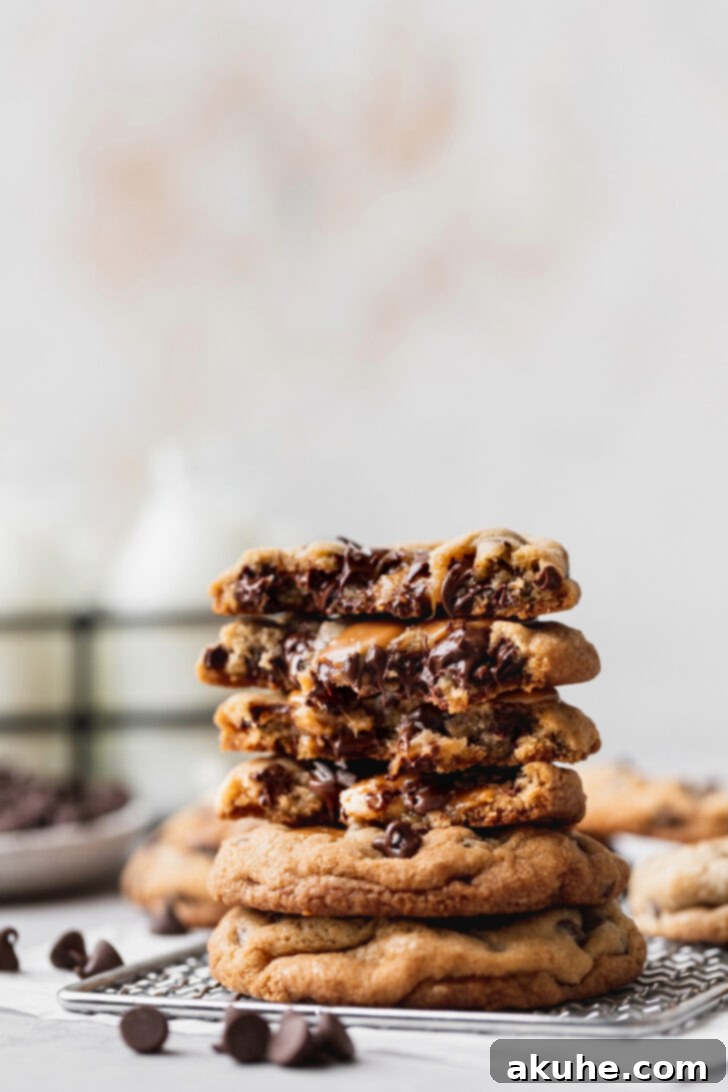 Gooey Caramel Chocolate Chip Cookies 9 A stack of golden brown caramel chocolate chip cookies, with one cookie split in half to beautifully reveal its molten caramel center and rich chocolate chips.