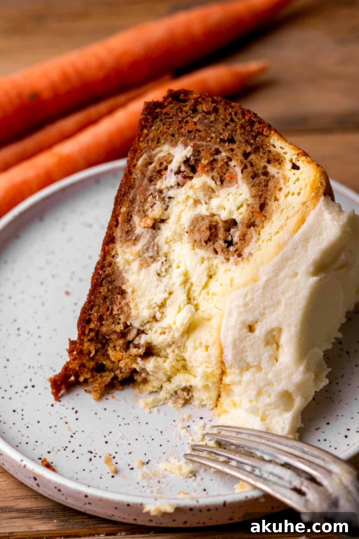 Carrot Cake Swirl Cheesecake 13 A pristine slice of carrot cake cheesecake on a simple white plate, ready to be eaten.