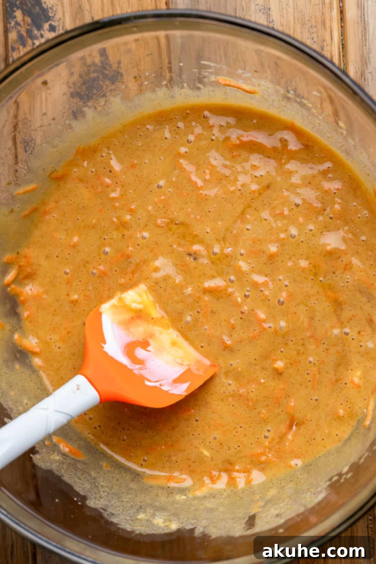 Carrot Cake Swirl Cheesecake 5 A glass bowl containing the wet ingredients for the carrot cake batter before dry ingredients are added.