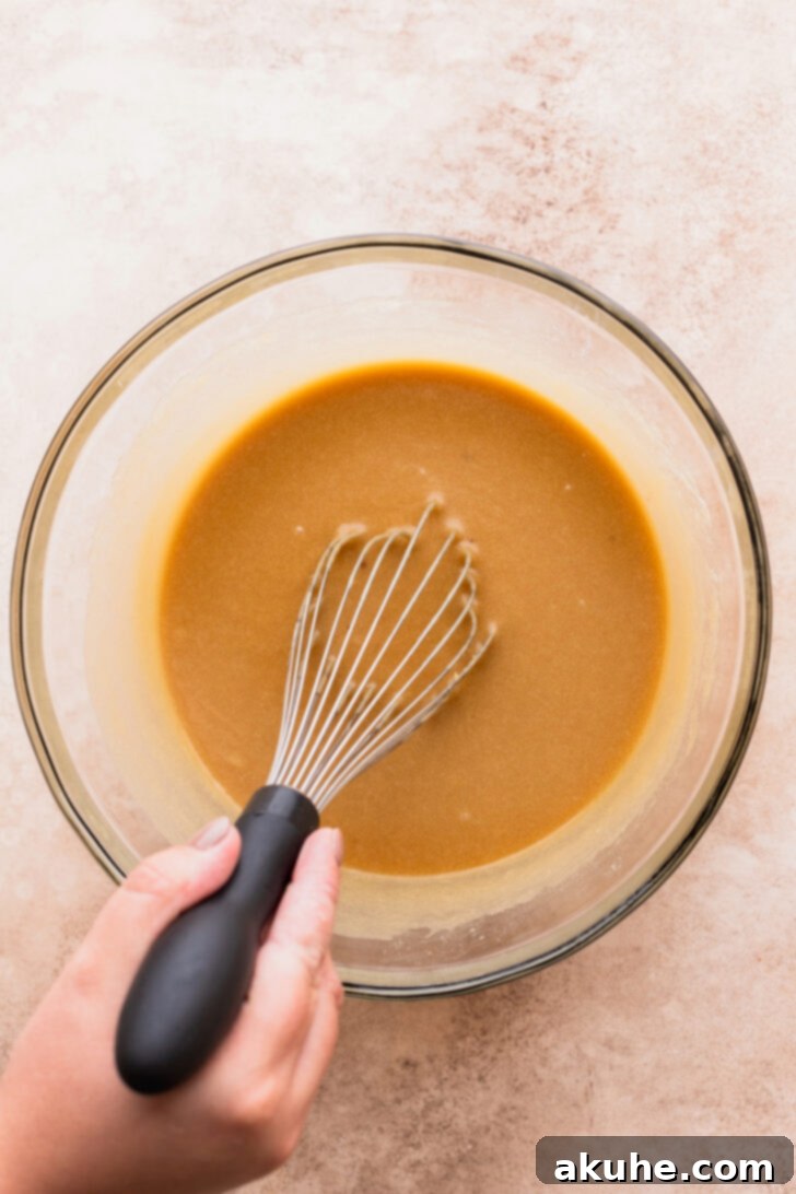 Decadent Caramel Apple Delight 4 Wet ingredients being mixed in a large bowl, a key step in creating the cake batter.