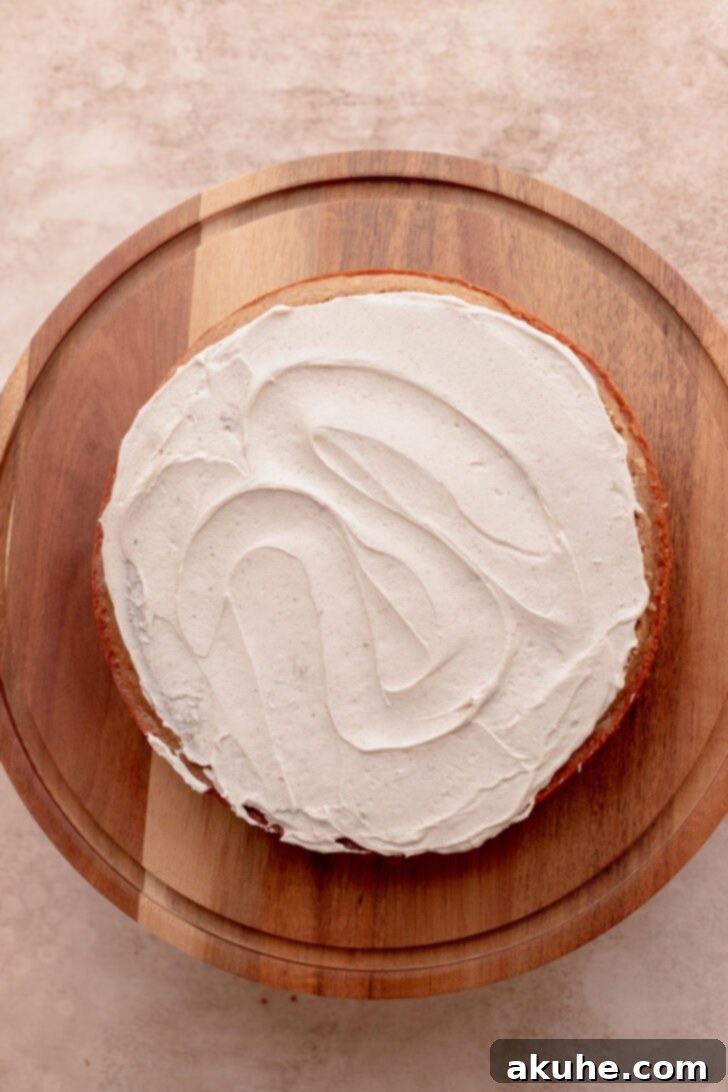 Decadent Caramel Apple Delight 8 First cake layer topped with a generous spread of caramel frosting.