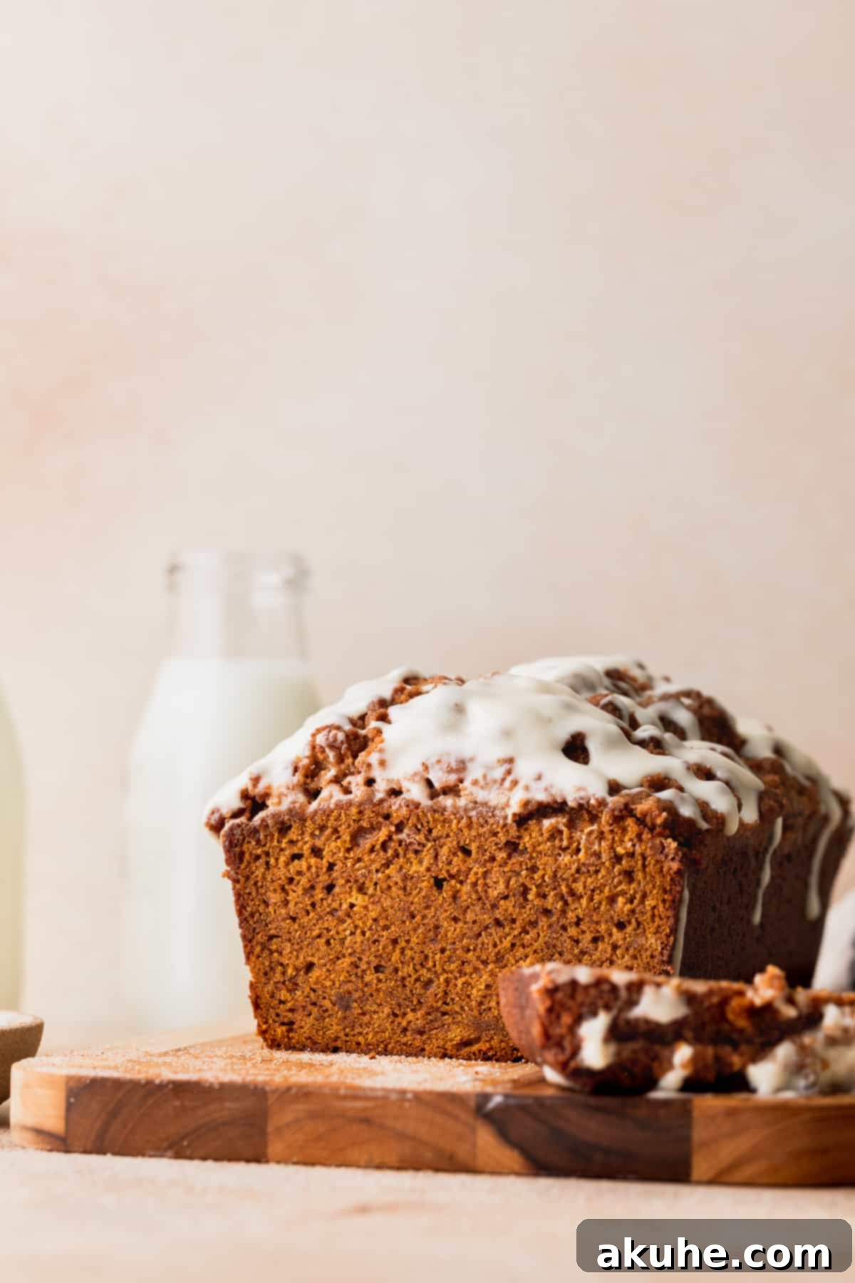 Spiced Pumpkin Loaf with Cream Cheese Frosting 2 Pumpkin bread with cream cheese frosting on a wood board, garnished with a dusting of cinnamon.