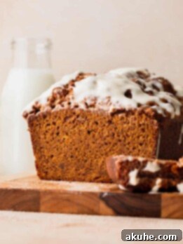 Spiced Pumpkin Loaf with Cream Cheese Frosting 12 Pumpkin bread with cream cheese frosting on a wood board.