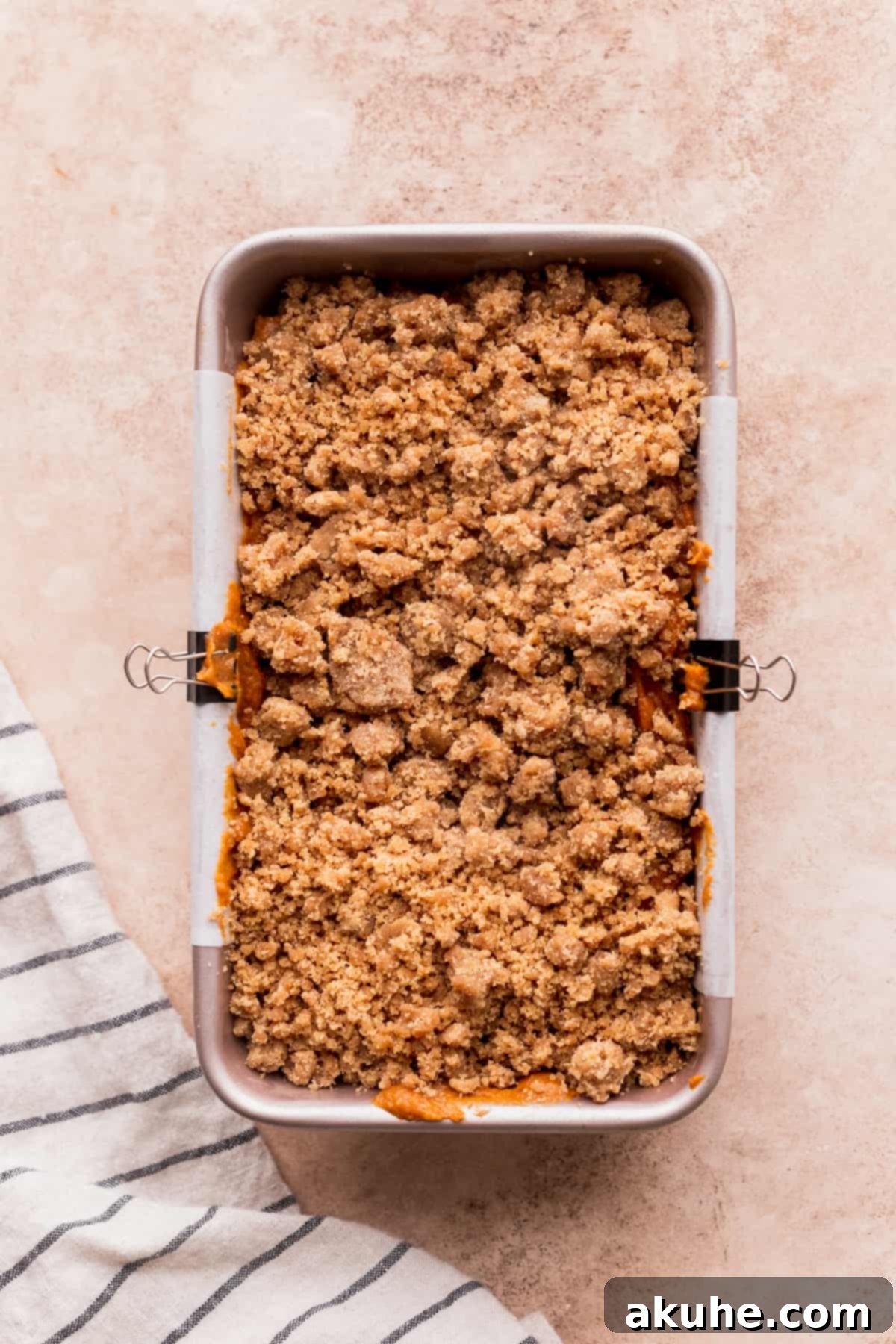 Spiced Pumpkin Loaf with Cream Cheese Frosting 8 Streusel topping sprinkled generously over pumpkin bread batter in a loaf pan.