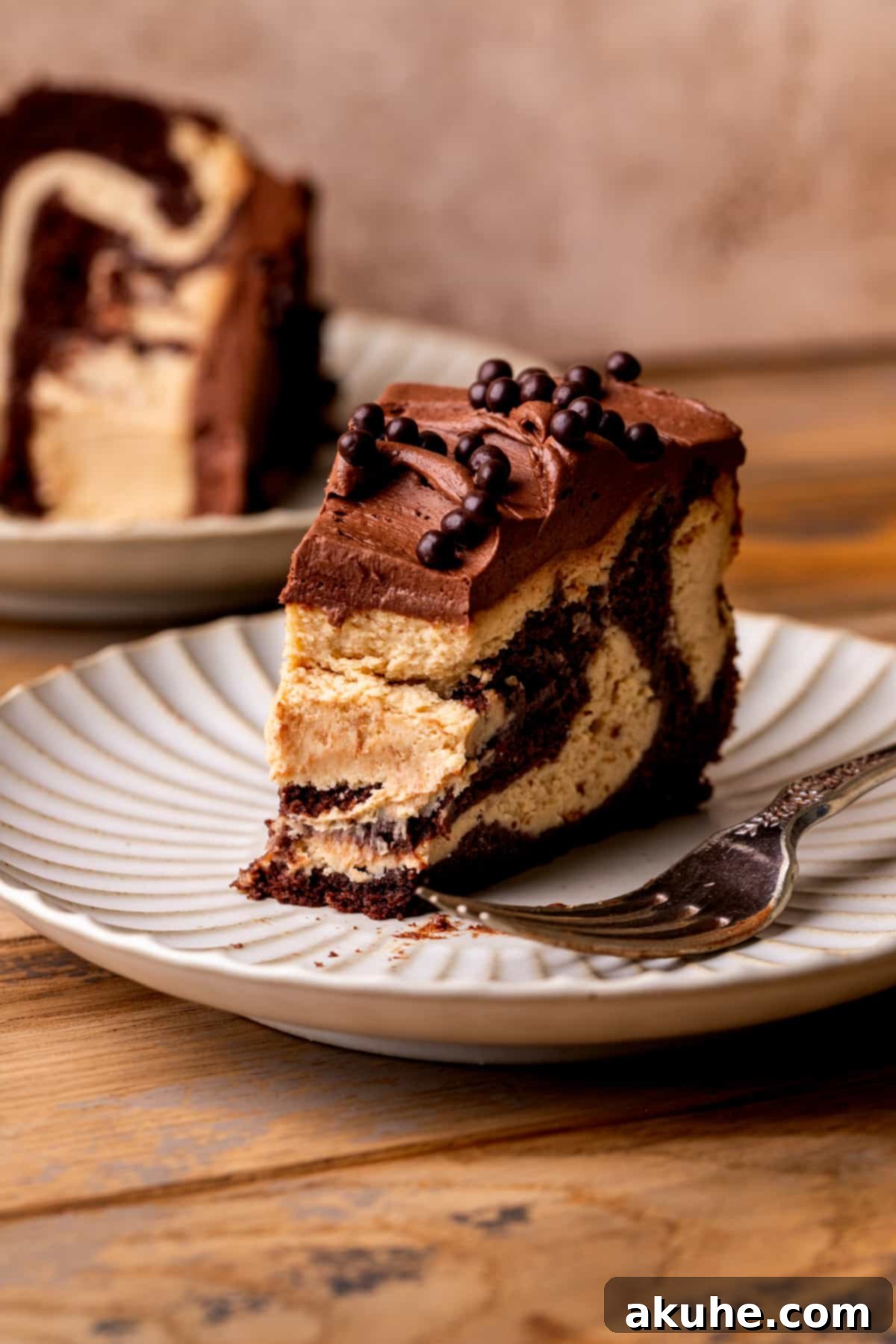 Ultimate Peanut Butter Chocolate Cheesecake 11 A piece of chocolate peanut butter cheesecake on a plate with a bite taken out, showing the creamy texture.