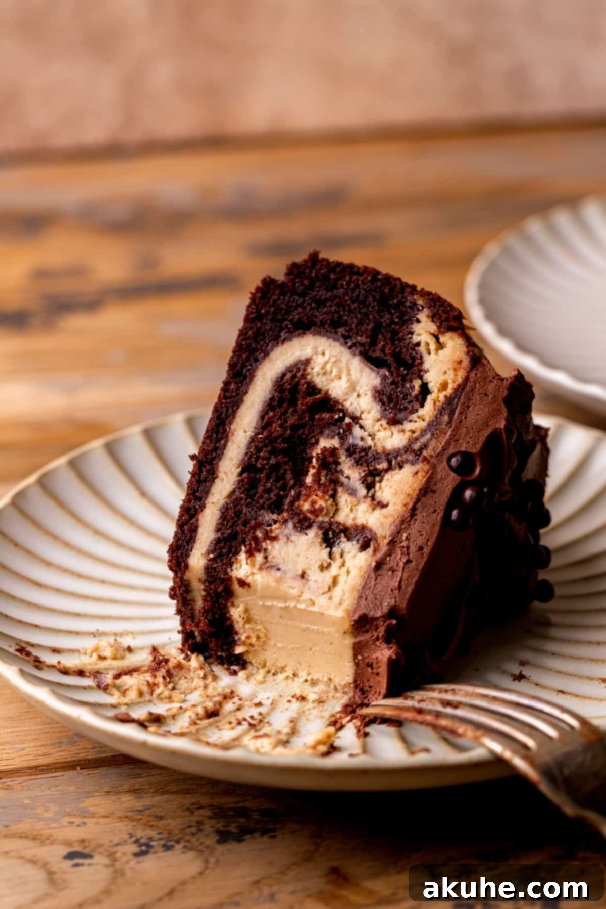 Ultimate Peanut Butter Chocolate Cheesecake 12 A closer view of a bite missing from a slice of chocolate peanut butter cheesecake on a plate, highlighting the delicious layers.