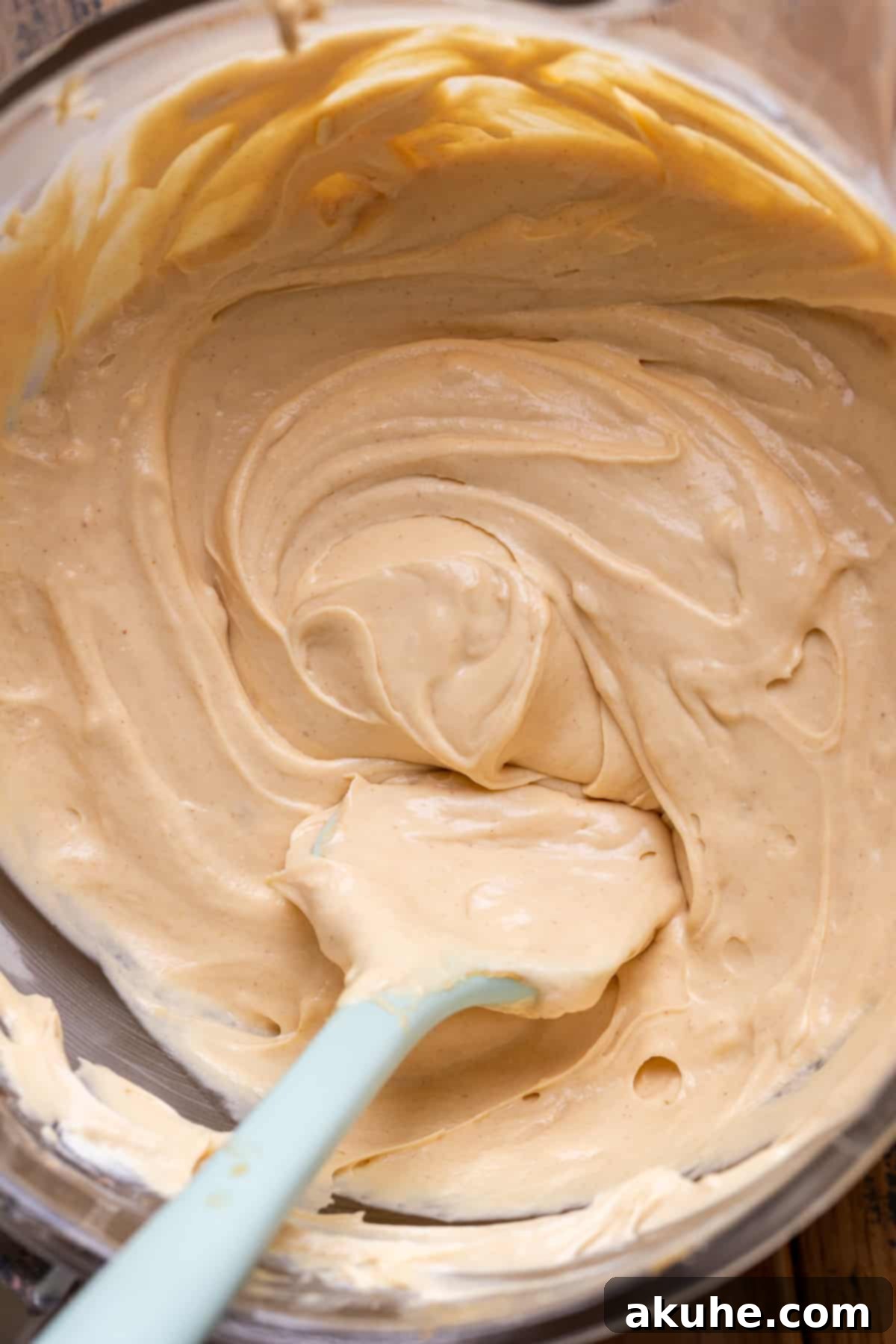 Ultimate Peanut Butter Chocolate Cheesecake 4 Smooth, creamy peanut butter cheesecake batter resting in a clear glass bowl, ready for assembly.