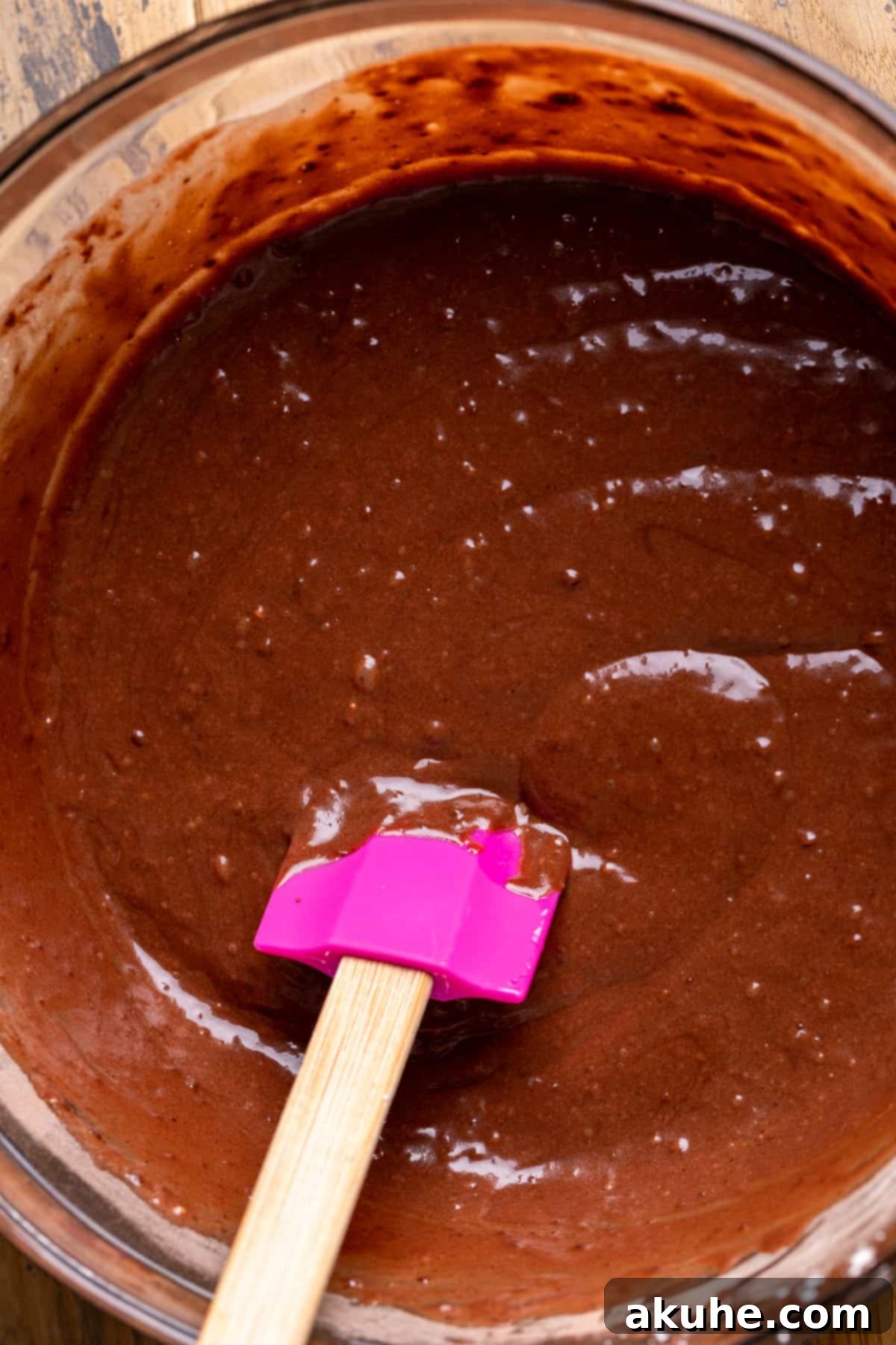 Ultimate Peanut Butter Chocolate Cheesecake 5 Rich chocolate cake batter in a clear glass bowl, showcasing its smooth consistency.