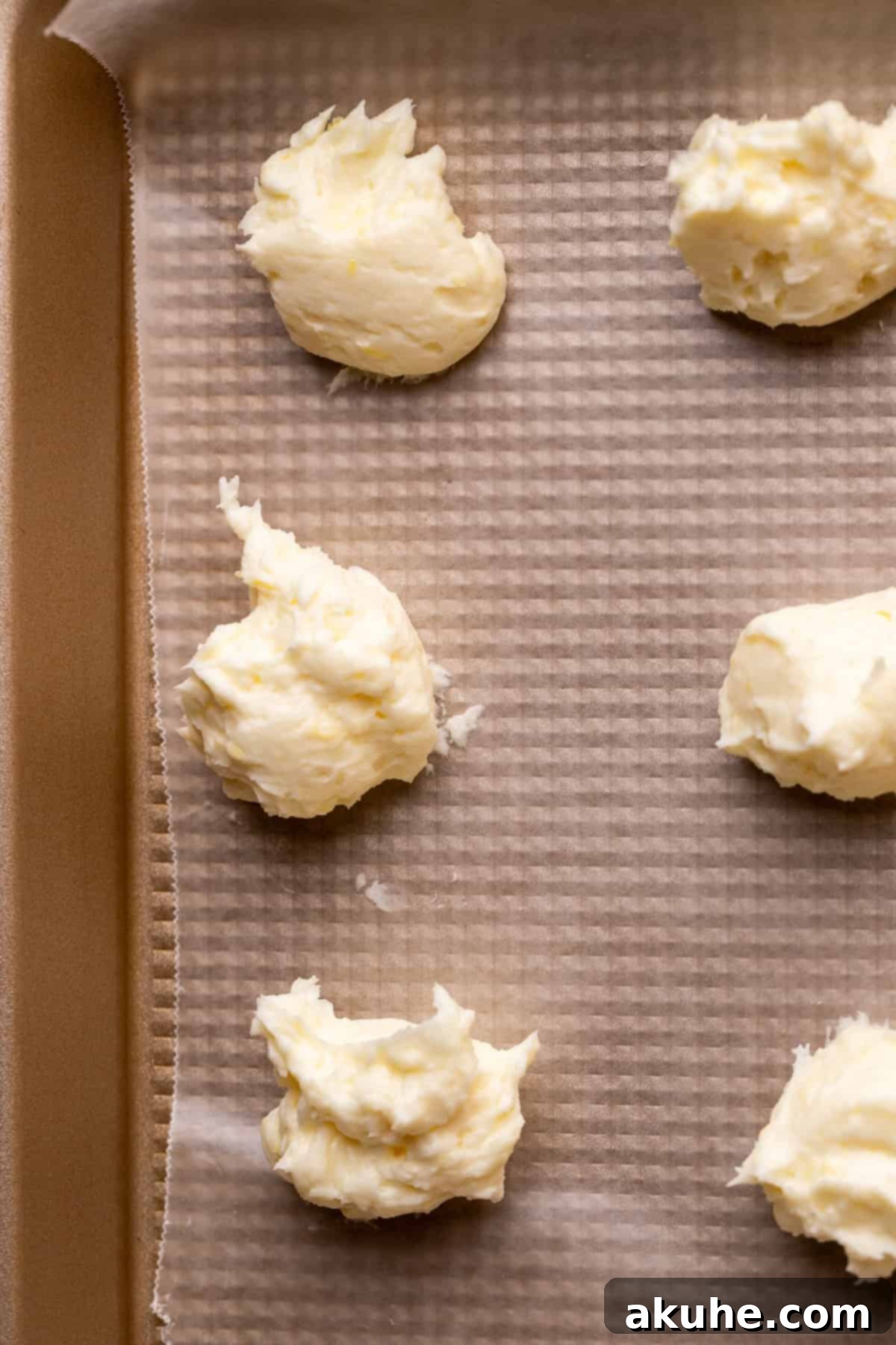 Zesty Lemon Poppy Seed Cookies 4 Lemon cheesecake dollops neatly arranged on a pan lined with wax paper.