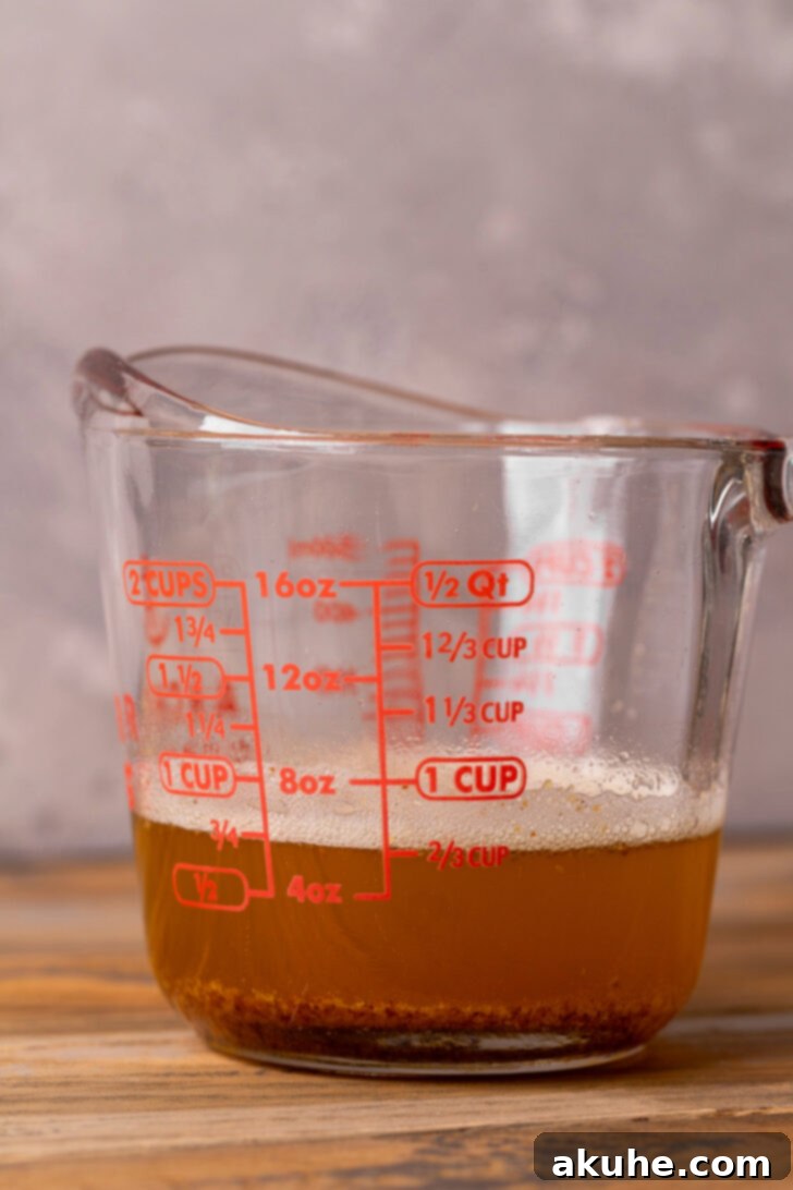 Nutty Brown Butter Chocolate Chip Cookie Slices 4 Golden brown butter in a clear glass measuring cup, showcasing its rich color and inviting texture.