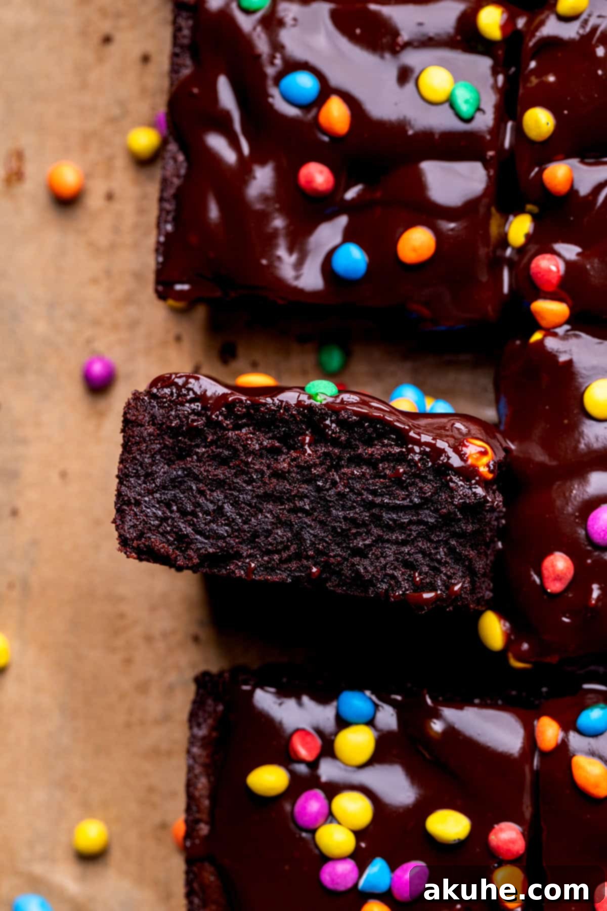 Decadent Cosmic Brownies 3 A single homemade Cosmic Brownie, artfully placed on its side, revealing its thick, fudgy center and generous ganache topping with colorful candies.