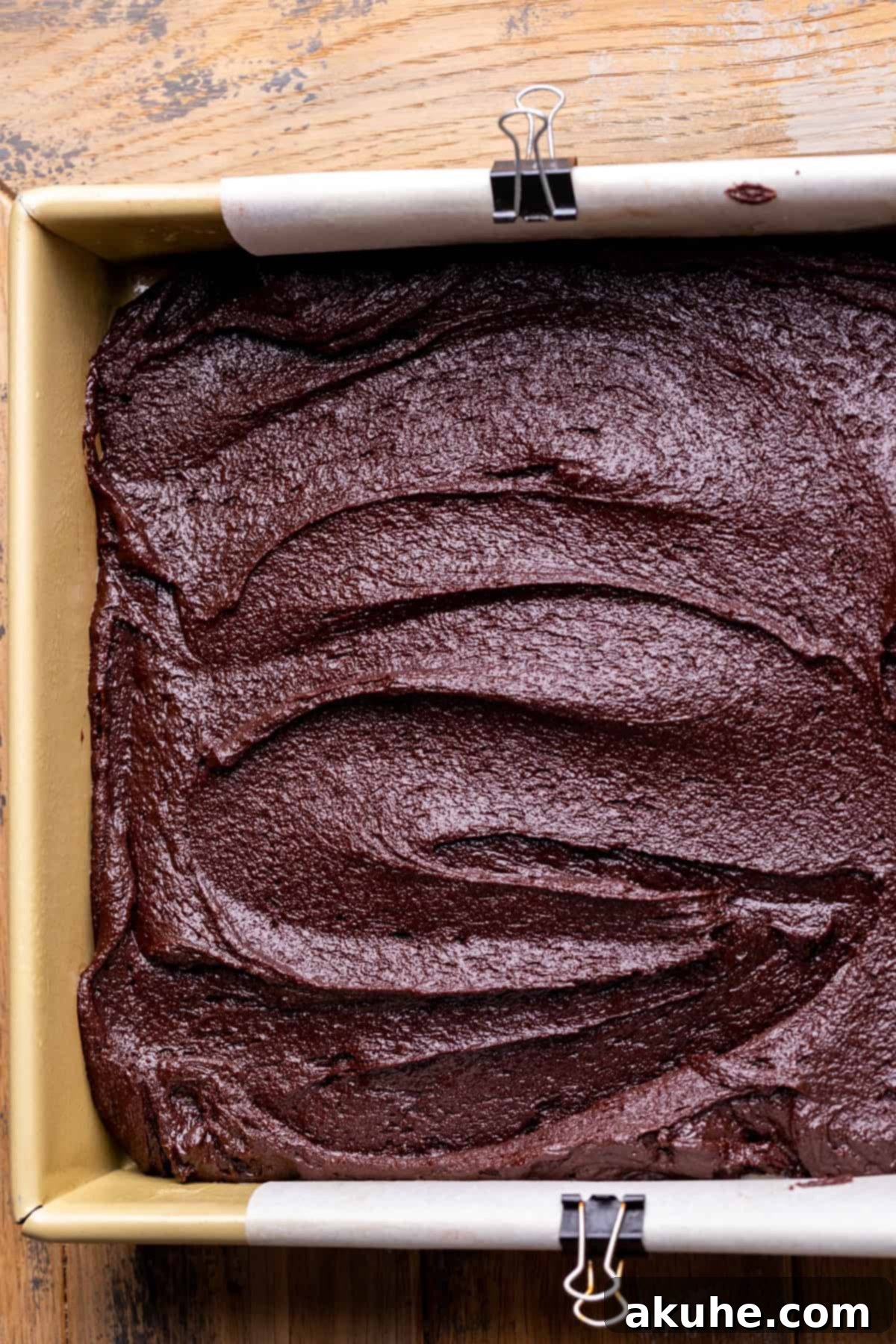 Decadent Cosmic Brownies 6 Thick brownie batter evenly spread in a parchment-lined square baking pan, ready for the oven.