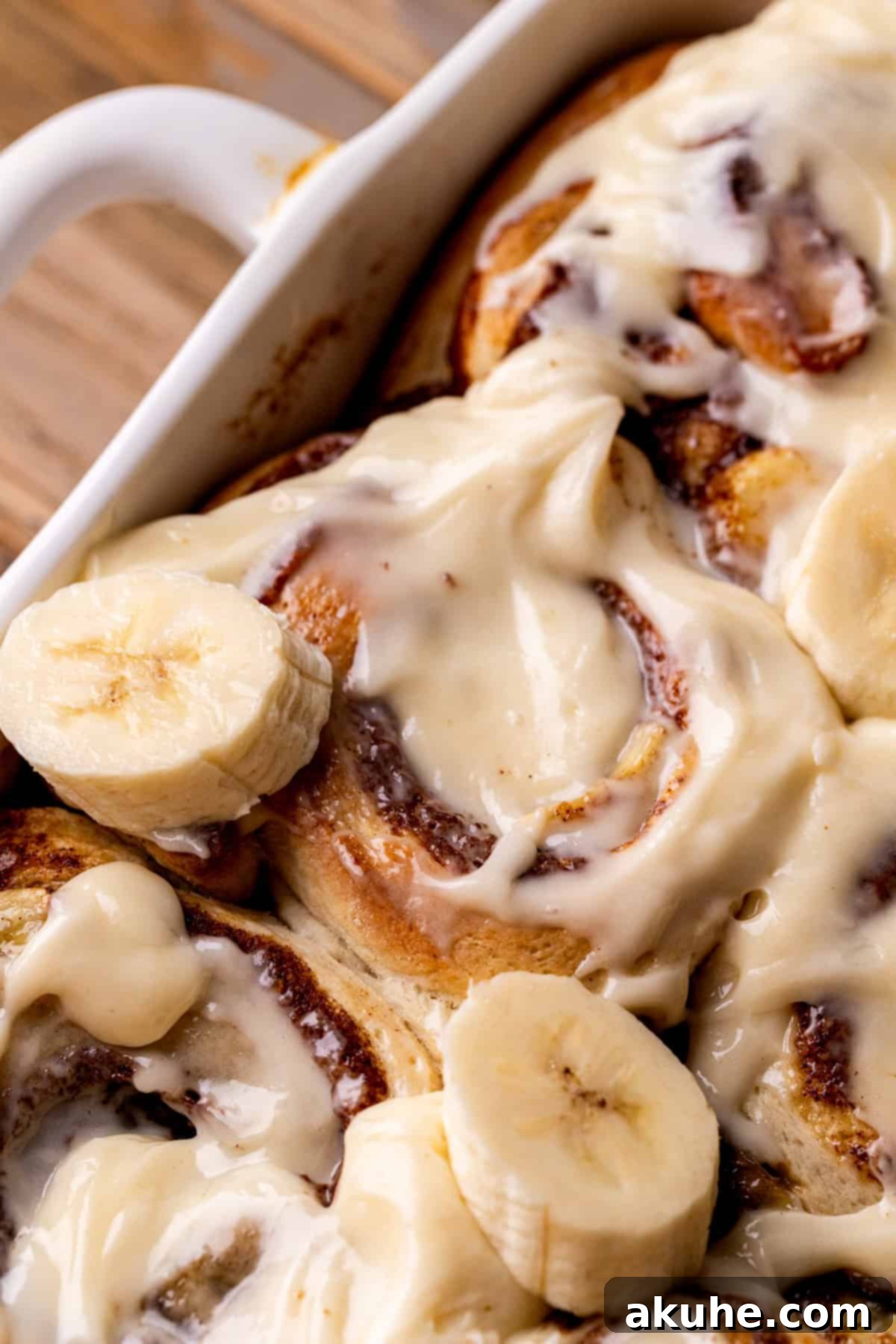 Banana Swirl Buns 2 Freshly baked Banana Cinnamon Rolls with cream cheese icing, arranged neatly in a baking pan.