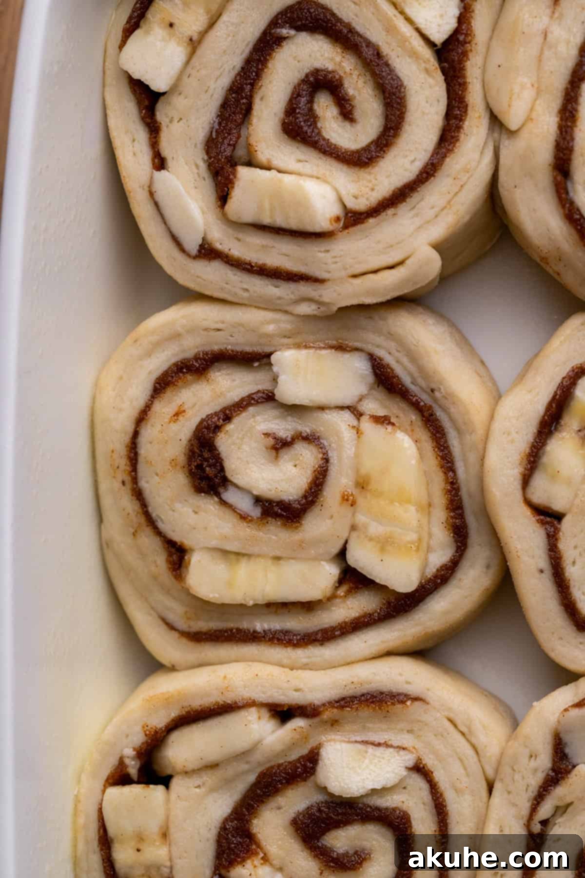 Banana Swirl Buns 6 Unbaked banana cinnamon rolls neatly arranged in a 9x13 inch baking pan, ready for the second rise.