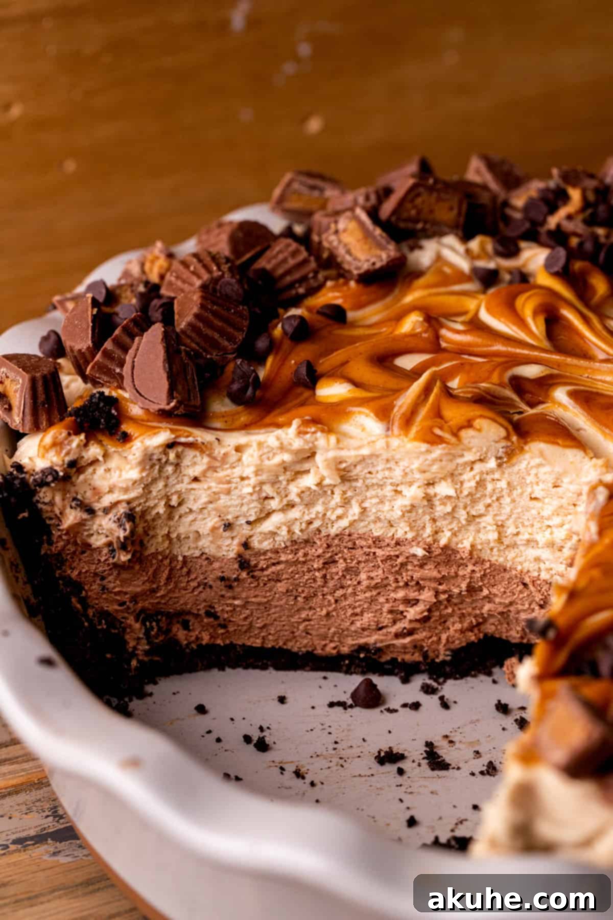 Side view of the assembled no-bake chocolate peanut butter pie still in its pie pan, showing its impressive height.