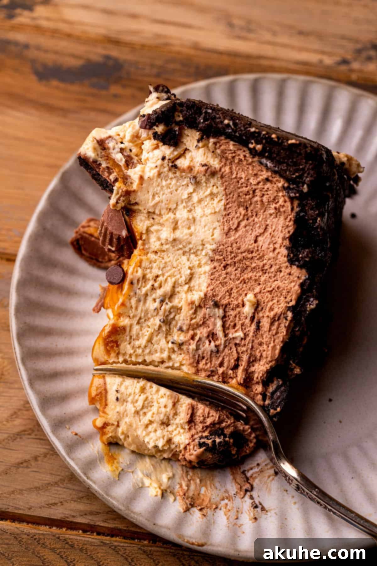 A slice of chocolate peanut butter pie with a fork inserted, showing the creamy layers.