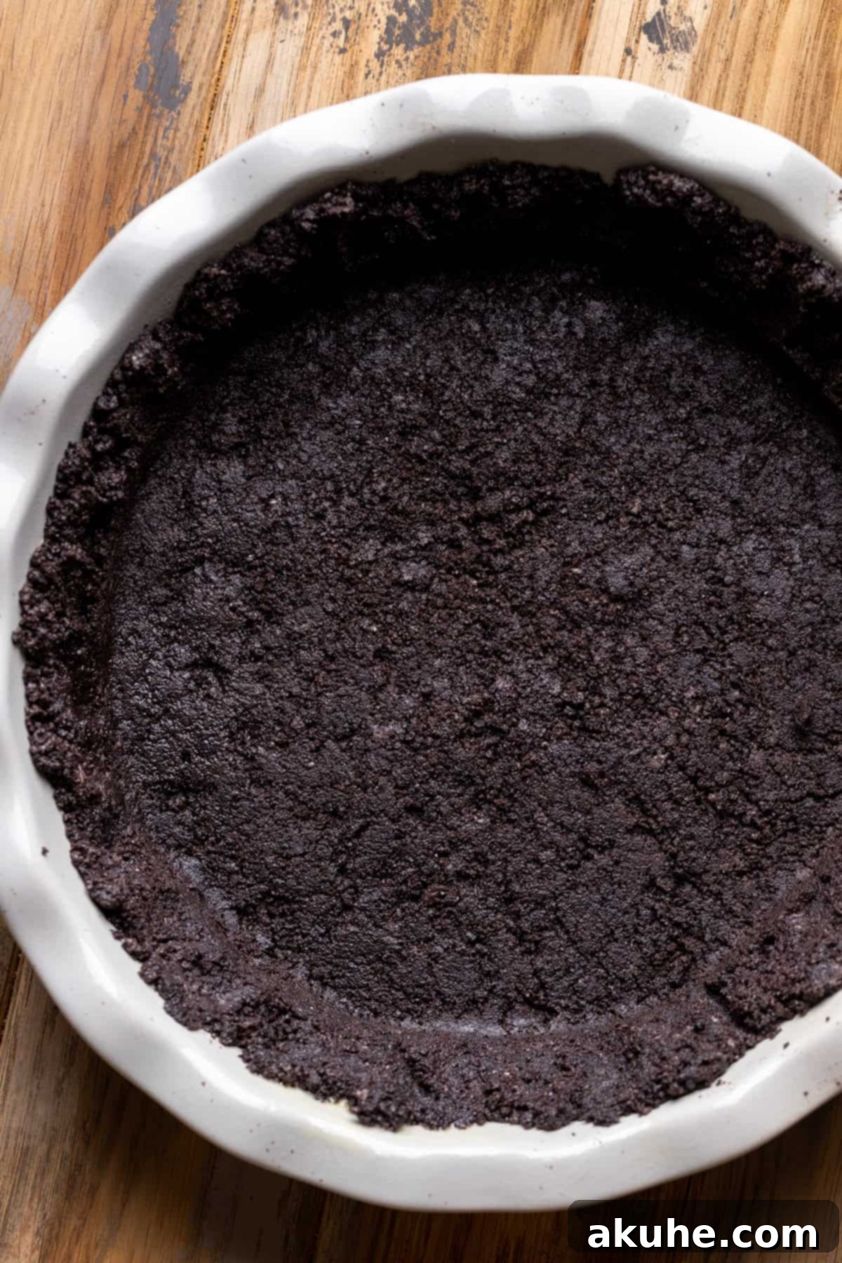 Close-up of a perfectly formed Oreo cookie crust in a pie pan, ready for filling.