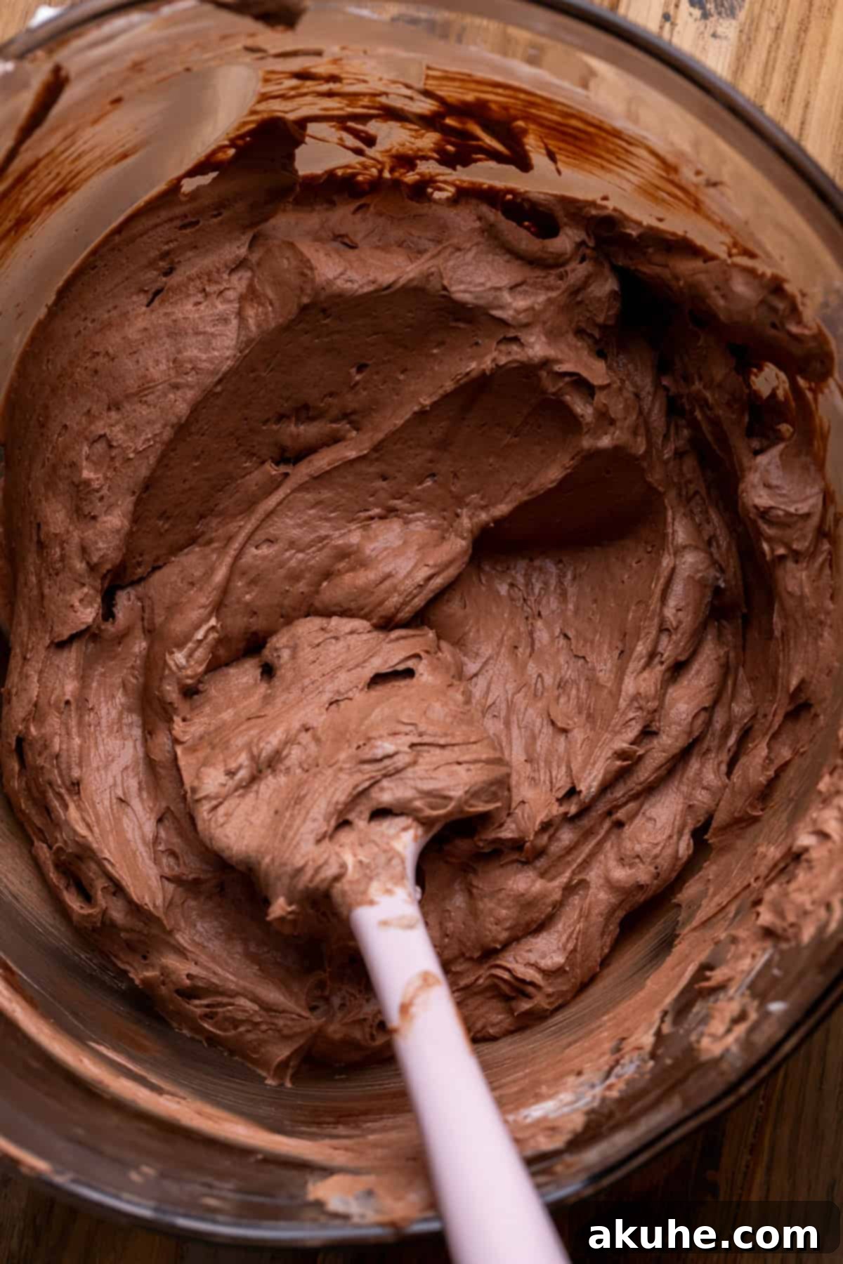 Light and airy whipped cream being gently folded into the chocolate pie batter in a bowl.