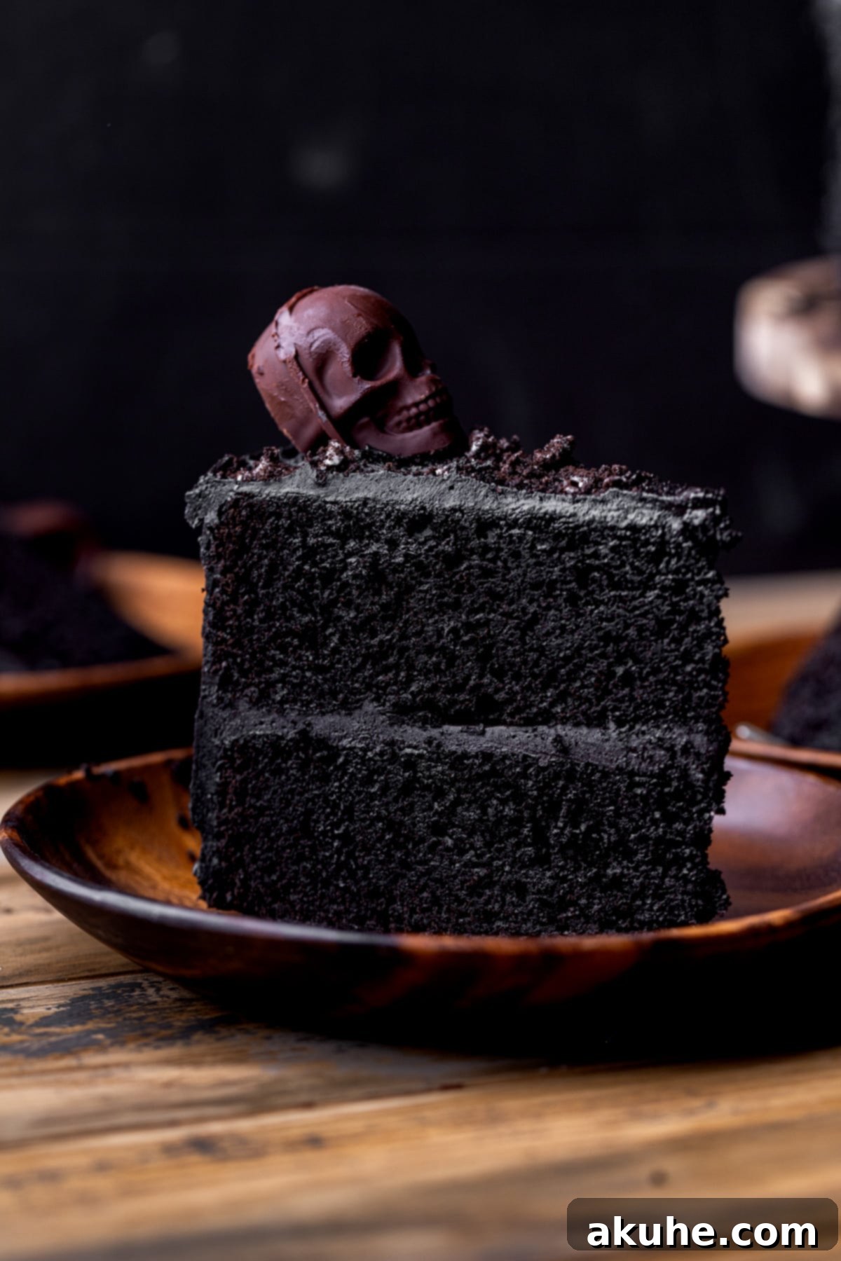 Bewitching Halloween Chocolate Cake 11 A single, elegant slice of the Halloween chocolate cake presented on a white plate, showcasing its moist texture and rich black color.