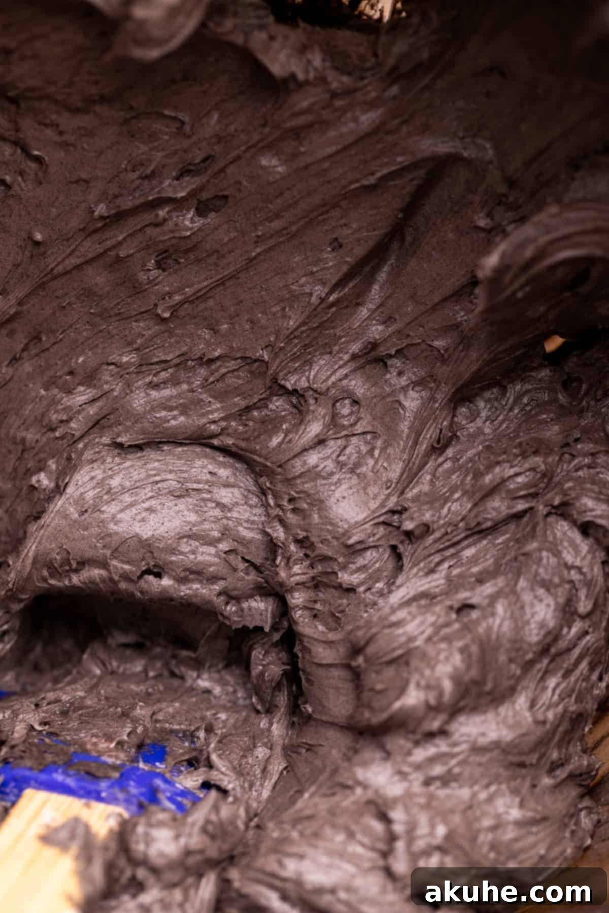 Bewitching Halloween Chocolate Cake 7 Rich black cocoa frosting in a clear glass bowl, showcasing its smooth and creamy texture.