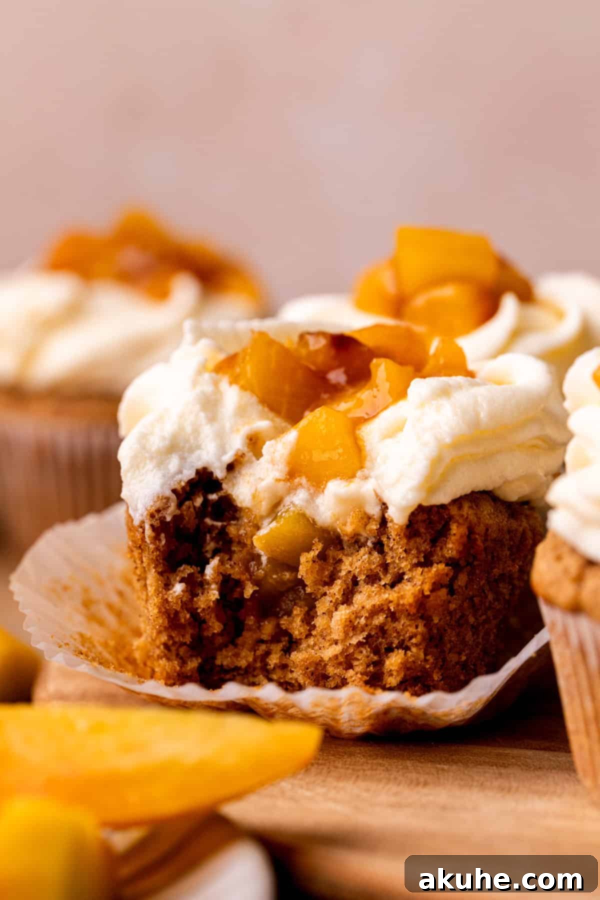 Bite missing from a peach cupcake, revealing the peach filling inside.