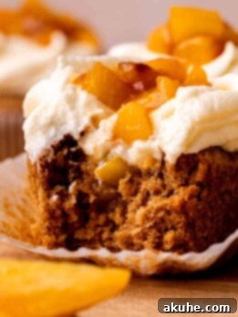 Bite missing from a peach cupcake.