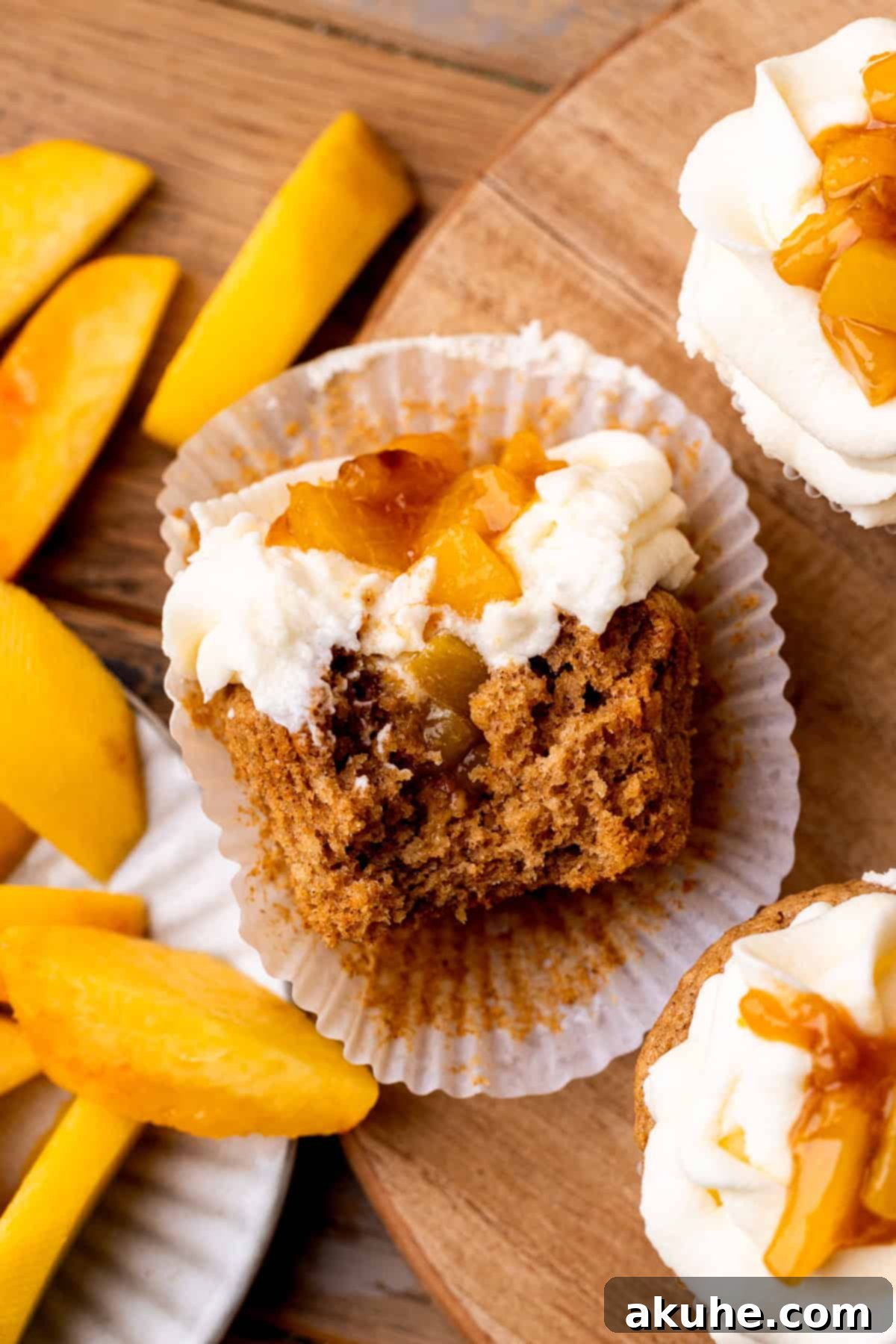 Top view of a bite missing from a peach cupcake, showing the soft cake and fruit filling.