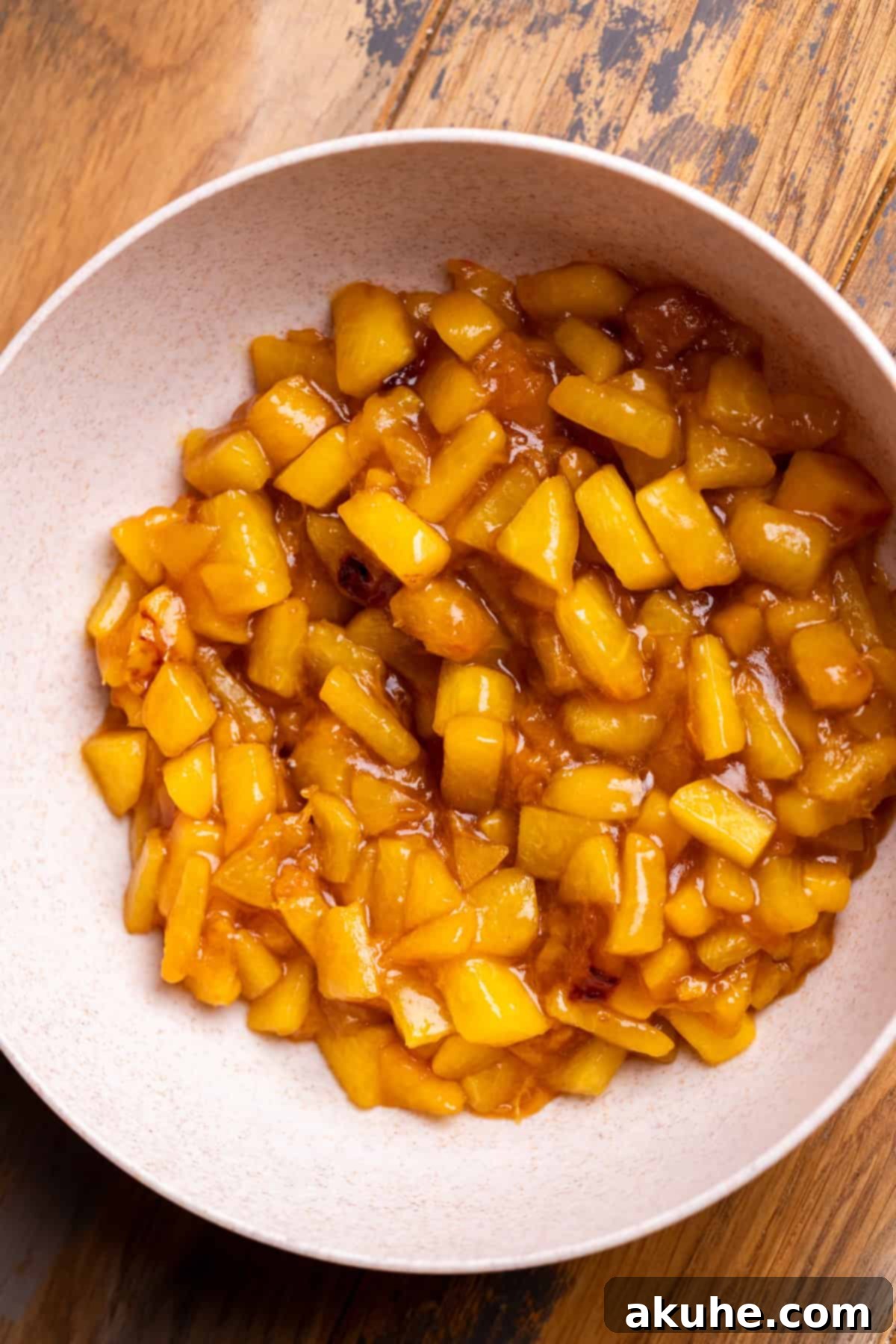 Homemade peach pie filling in a bowl, showing its thick and glossy texture.