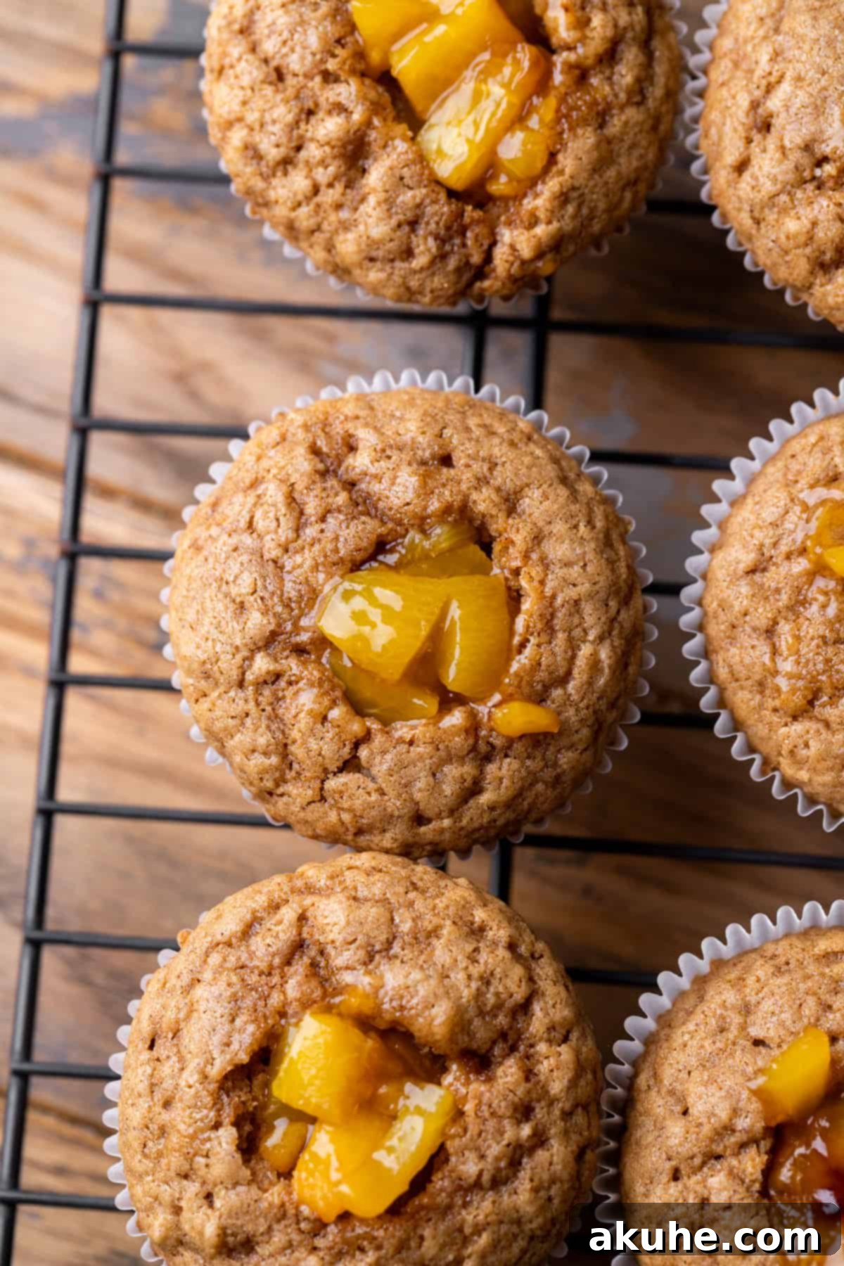 Cupcakes filled with peach pie filling, sitting on a wire rack before frosting.