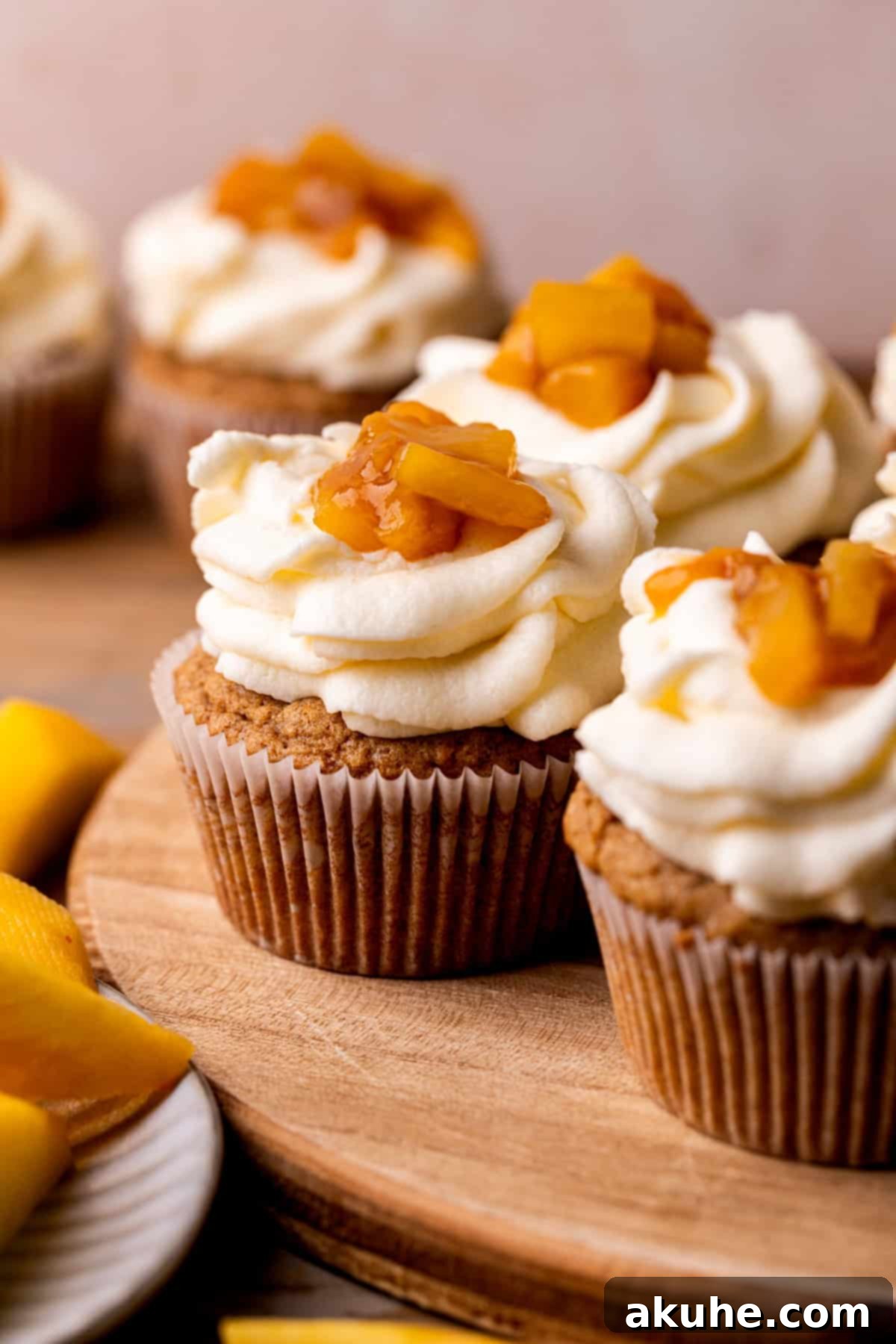 Beautifully decorated cinnamon peach cupcakes arranged on a rustic wood board.