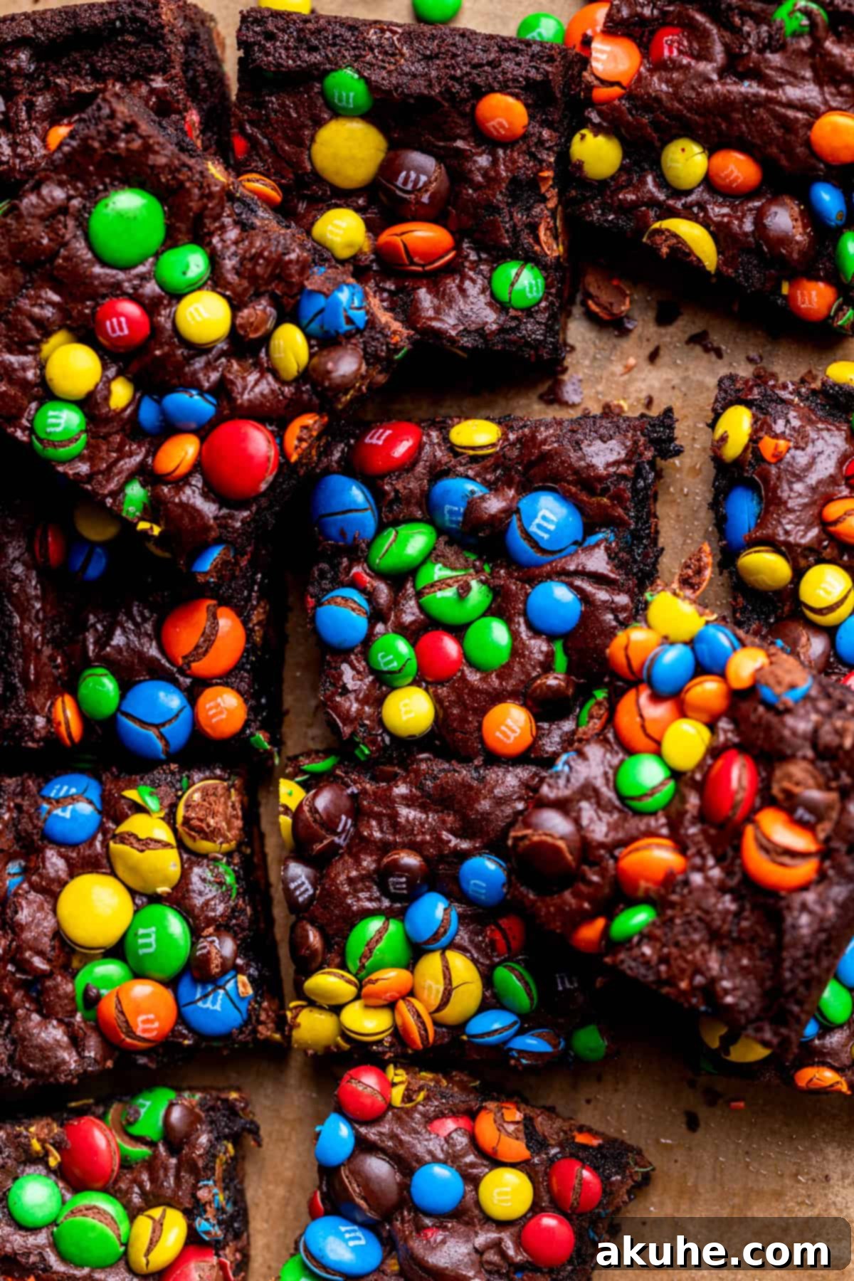 Decadent Fudgy M and M Brownies 2 M&M brownies on parchment paper, showcasing their fudgy texture and colorful candy topping.