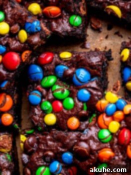 Decadent Fudgy M and M Brownies 11 M&M brownies on parchment paper, ready to be cut into squares.