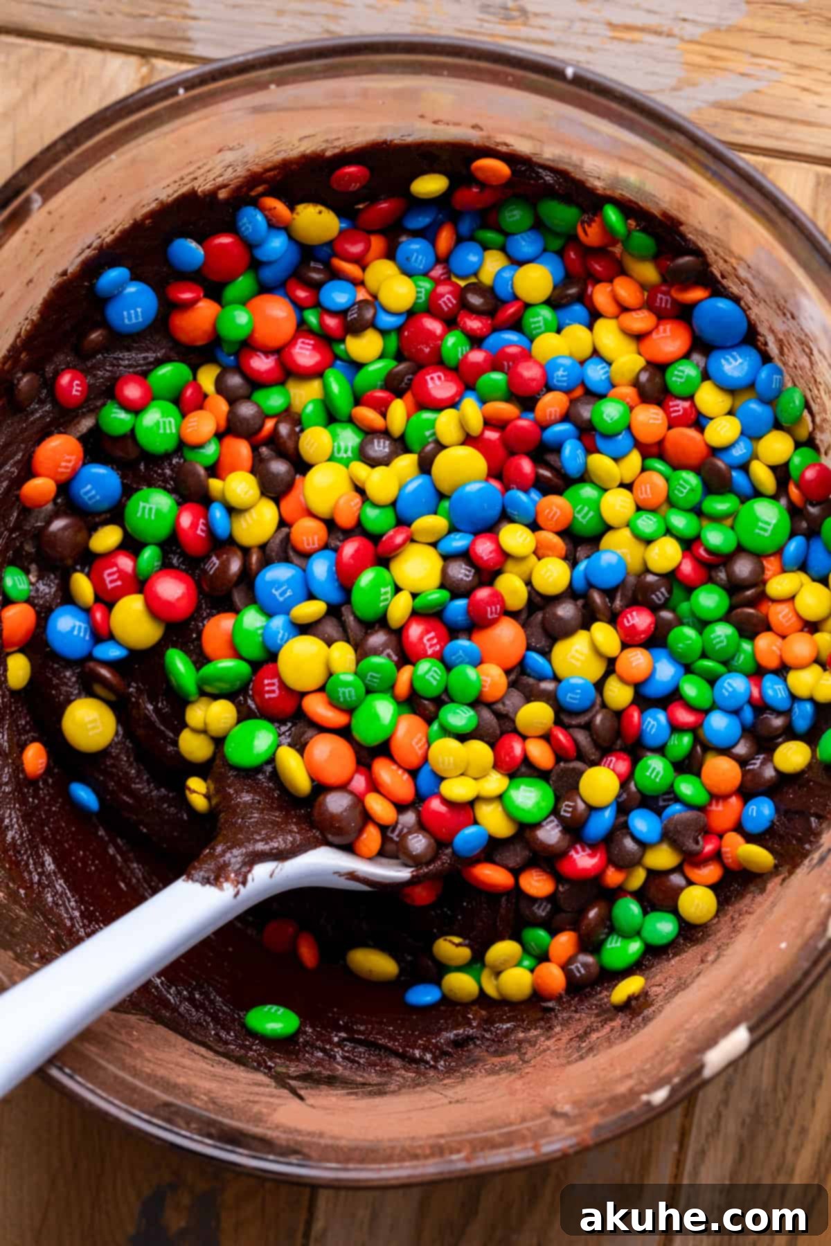 Decadent Fudgy M and M Brownies 5 Colorful M&M's scattered generously on top of rich brownie batter in a glass bowl, ready for mixing.