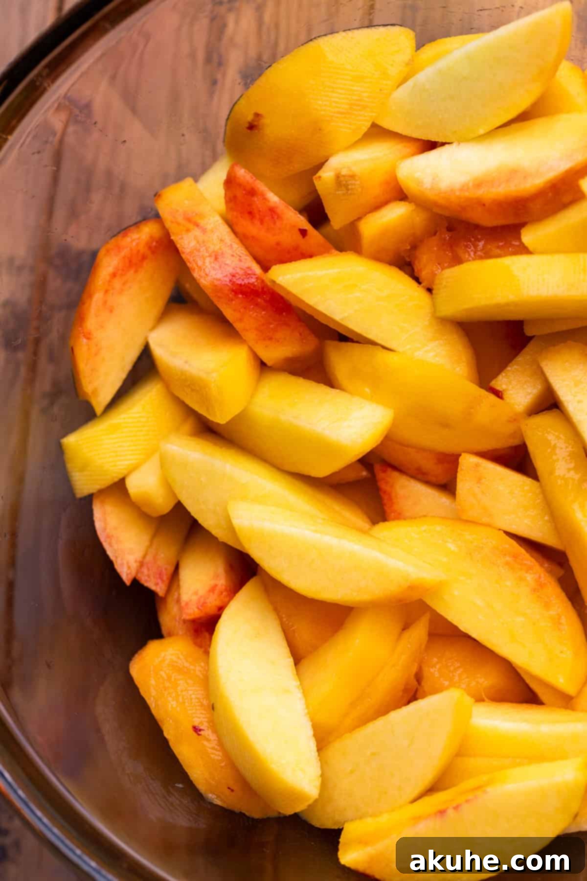 Freshly sliced peaches in a clear glass bowl, ready for seasoning.