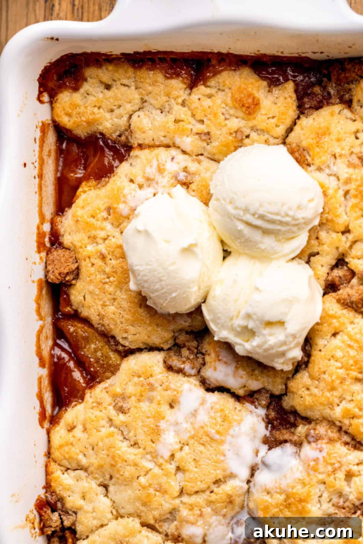 Freshly baked cinnamon peach cobbler with a golden biscuit topping in a glass baking pan.