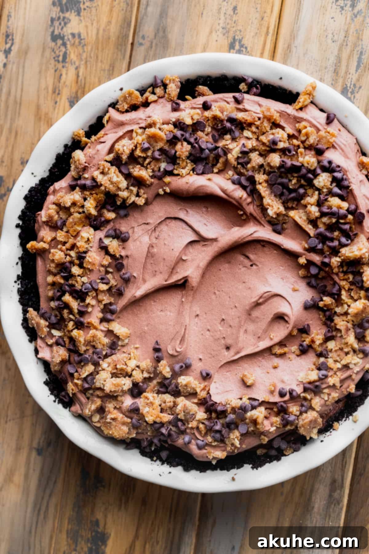 The fully decorated chocolate pie, topped with whipped cream and crumble, in its pan.