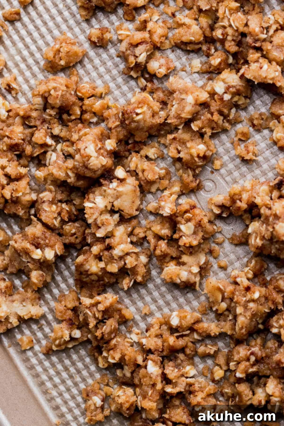 Unbaked oat crumble spread on a cookie sheet, ready for the oven.