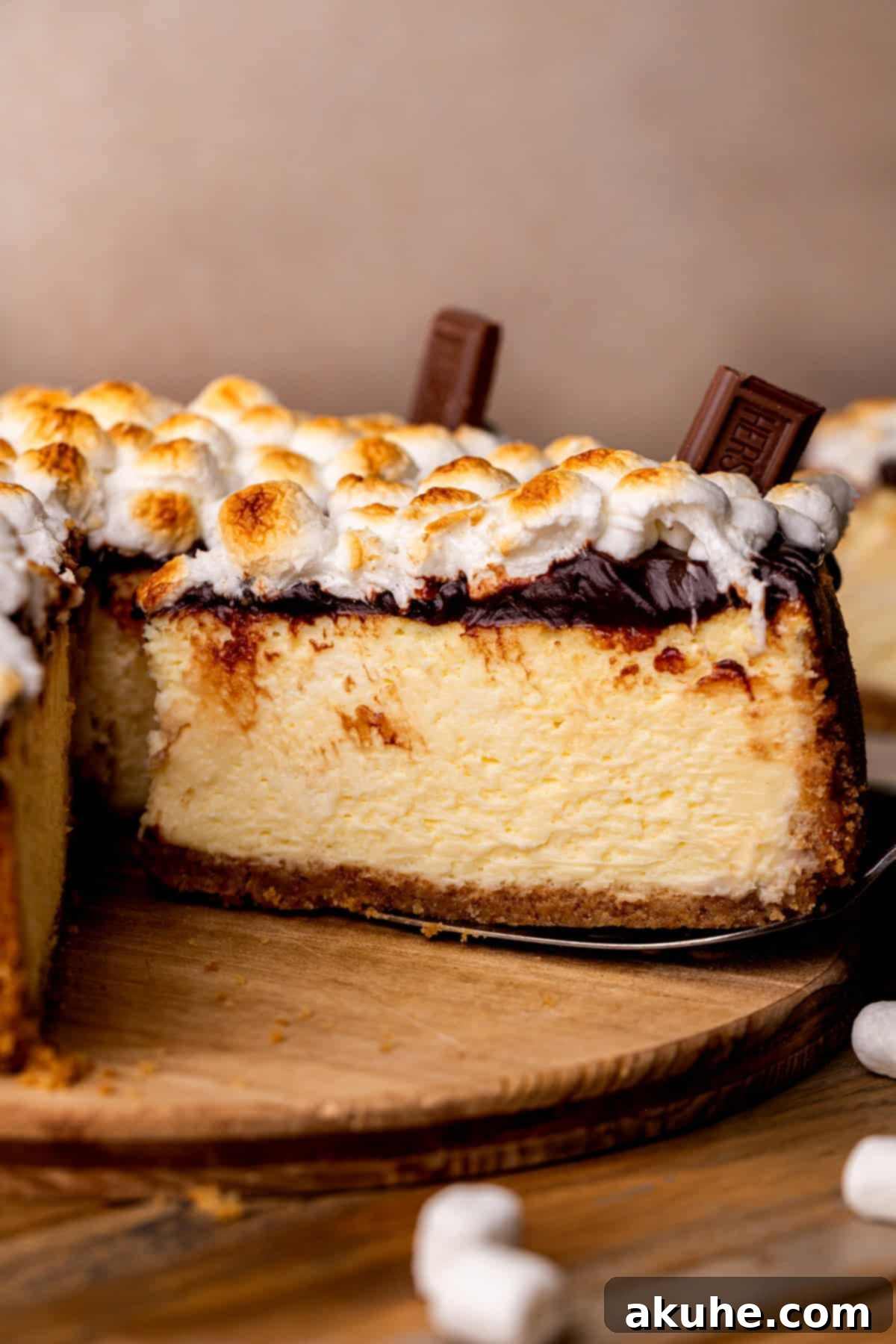 A hand taking a slice out of the S'mores cheesecake, showing its perfect layers.