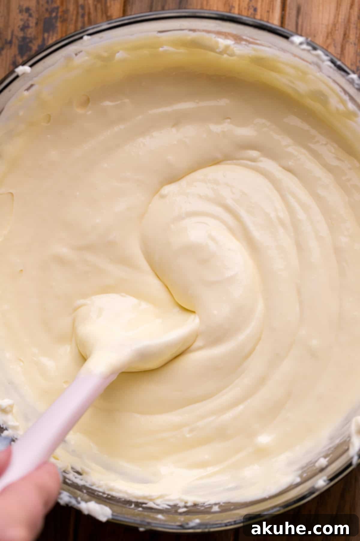 Smooth cheesecake batter in a glass bowl, ready to be poured into the crust.