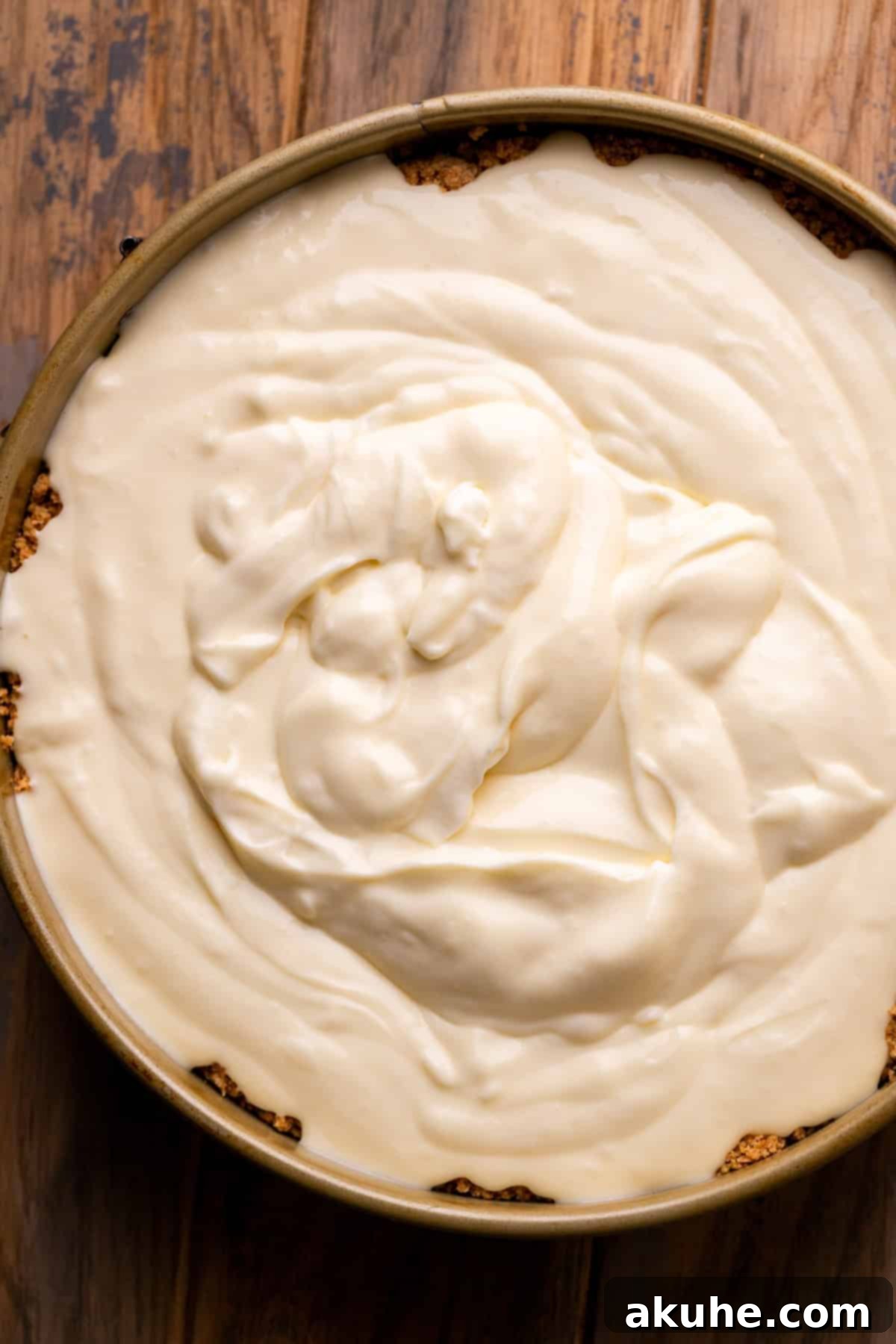 Cheesecake batter poured into the prepared graham cracker crust in a springform pan.