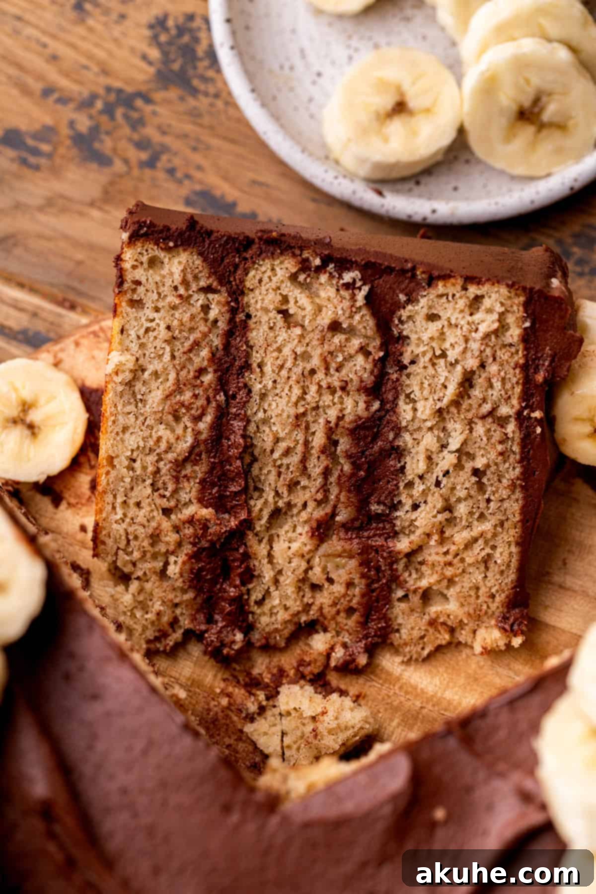 Decadent Banana Chocolate Dream Cake 3 A delectable slice of banana cake with chocolate frosting, viewed from above, showcasing its layers and rich topping.
