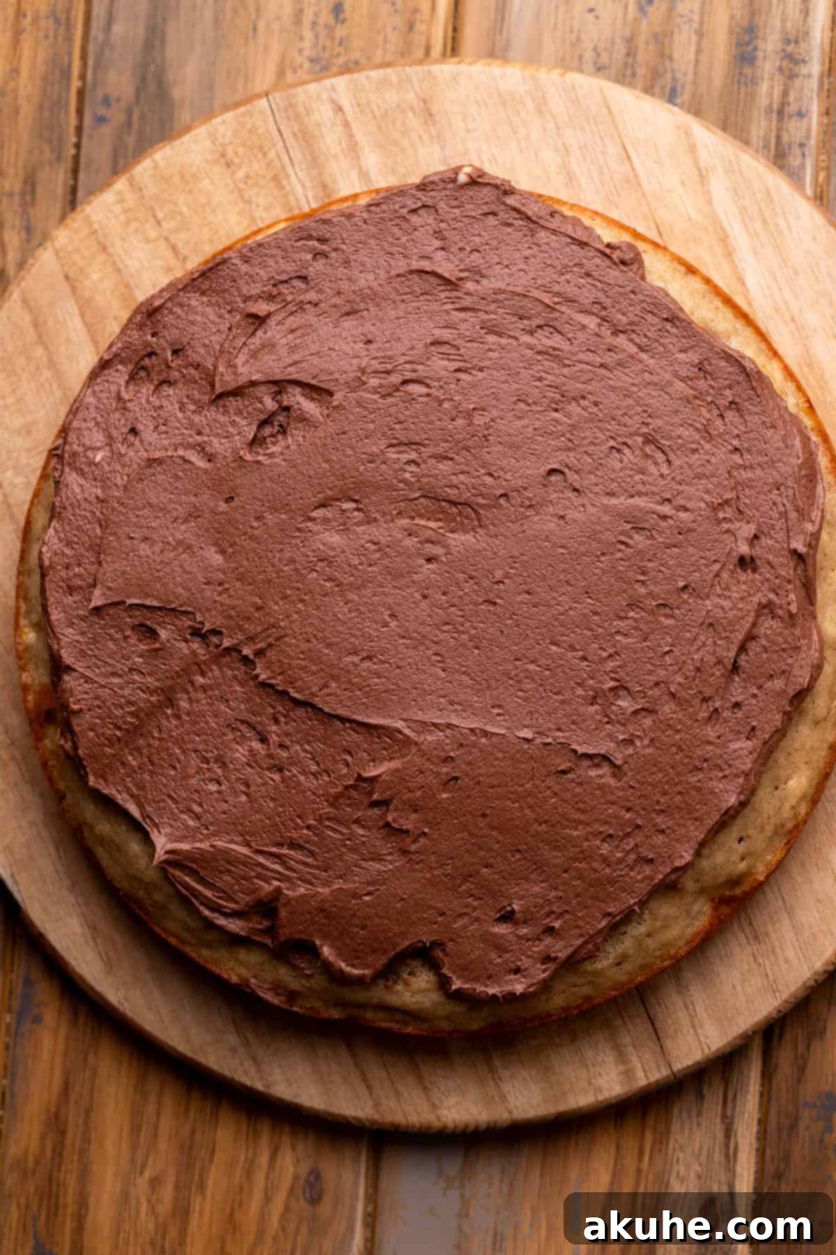 Decadent Banana Chocolate Dream Cake 8 A neatly frosted cake layer on a wooden board, showcasing the even application of chocolate cream cheese frosting.