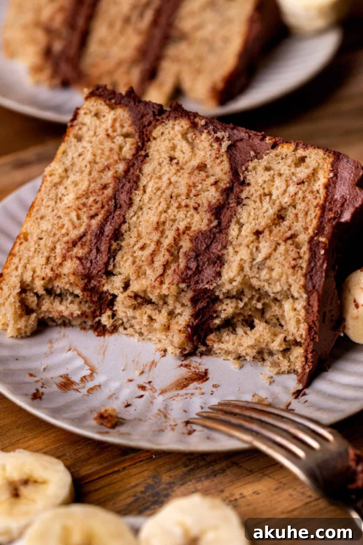 Decadent Banana Chocolate Dream Cake 10 A slice of banana cake with chocolate frosting on a plate, with a bite missing, highlighting its deliciousness.
