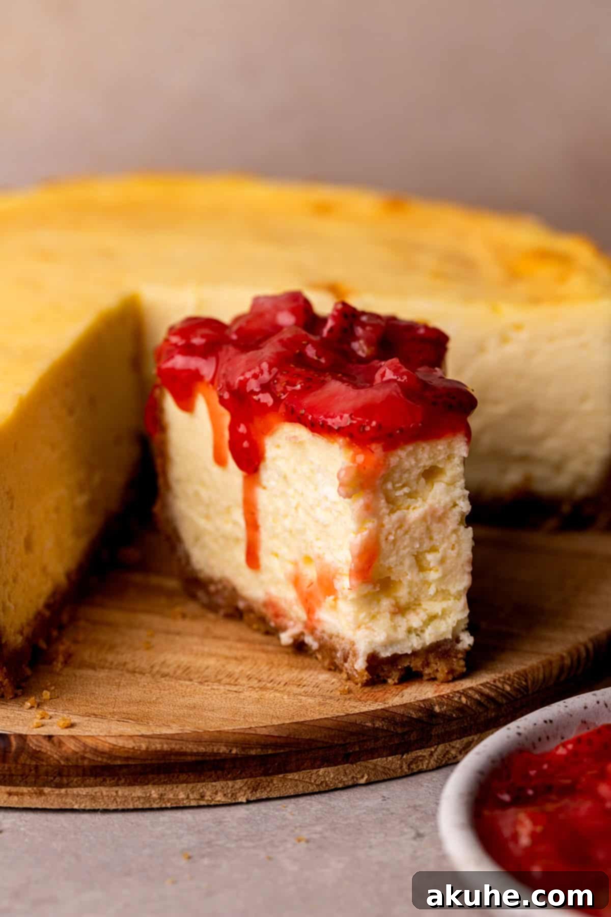 A perfectly sliced piece of New York style cheesecake on a wooden board, ready to be enjoyed.