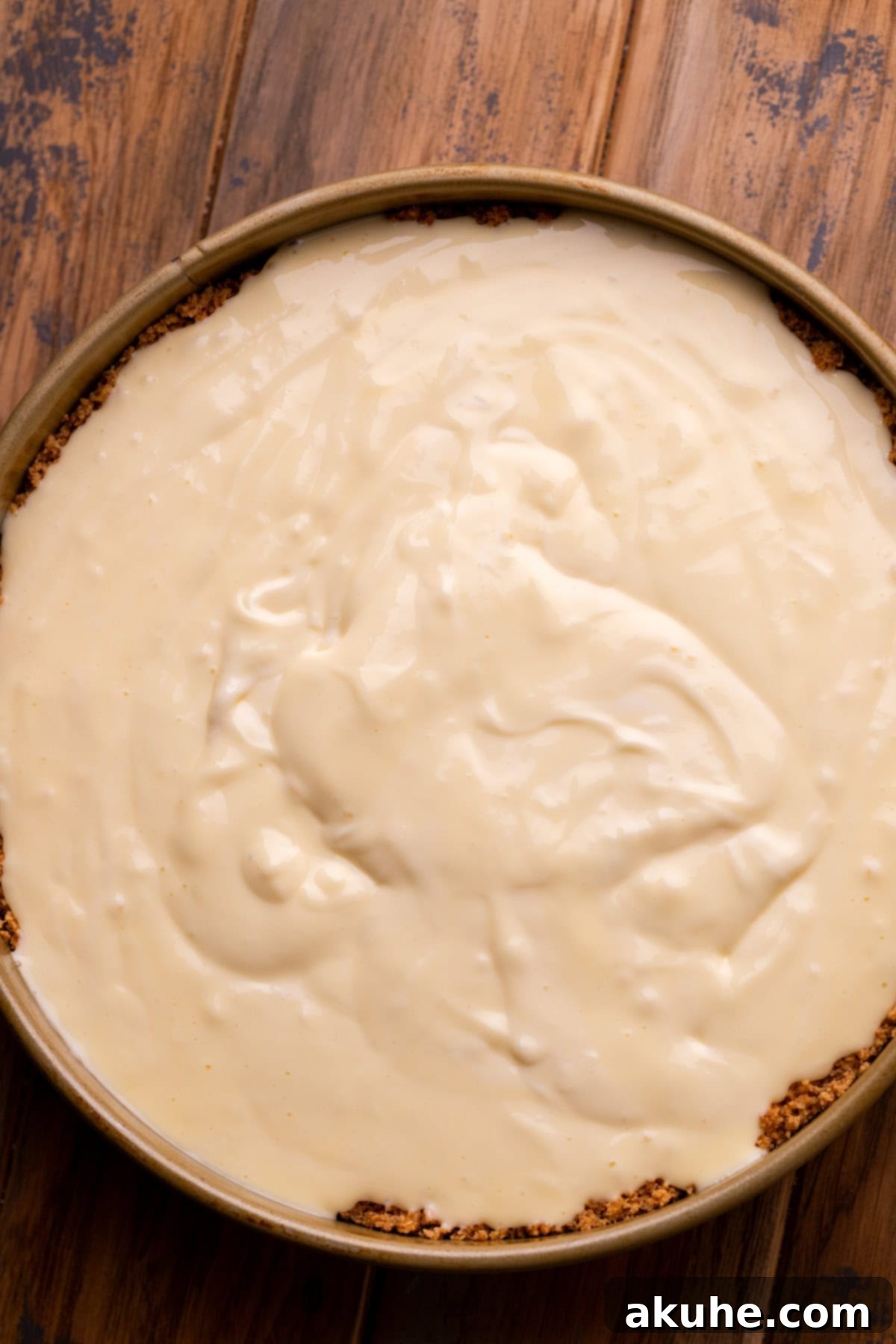 Cheesecake batter perfectly poured into the prepared crust in the pan.