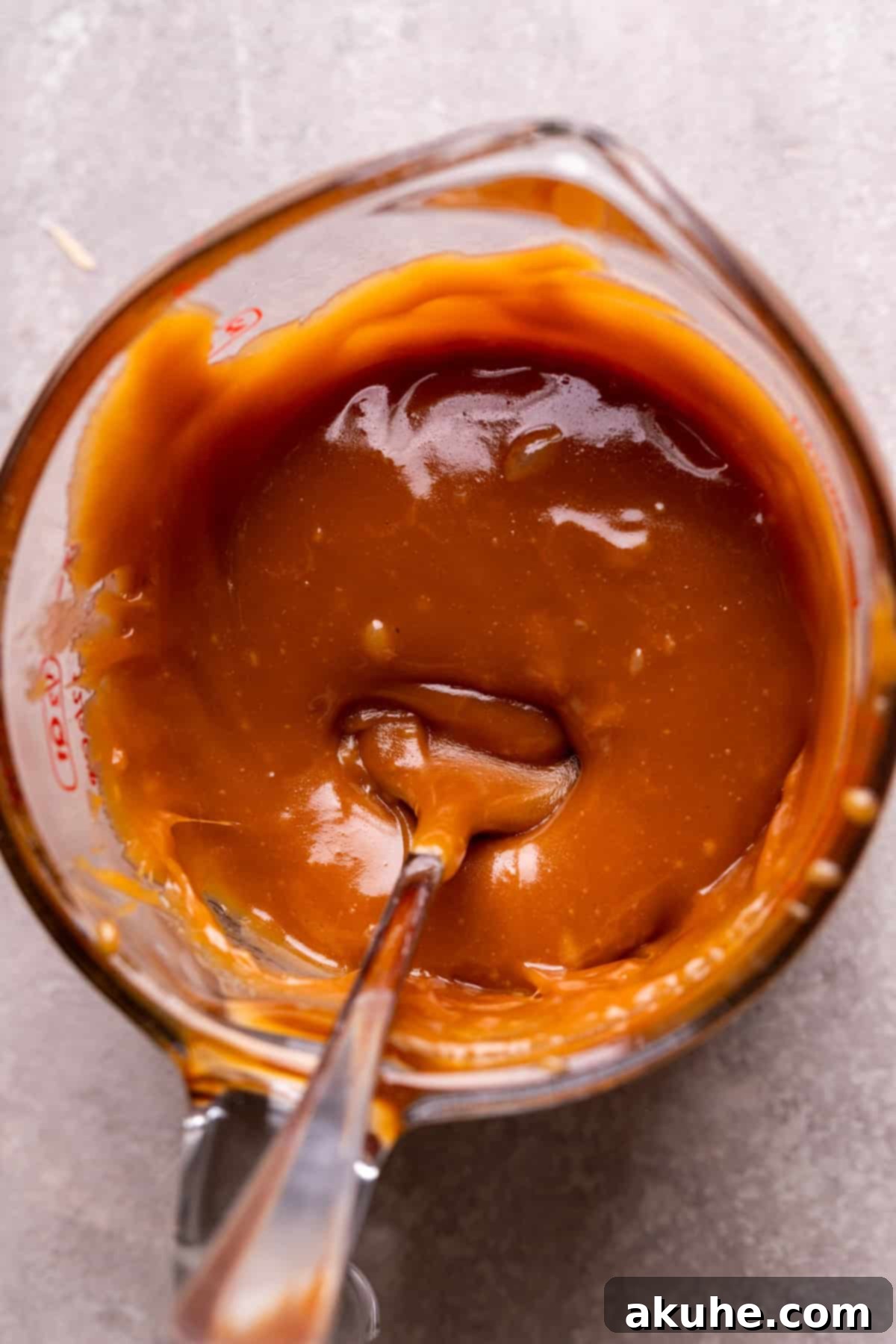 Decadent Caramel Cookie Bars 4 Luminous homemade caramel resting in a clear glass measuring cup, ready for incorporation.