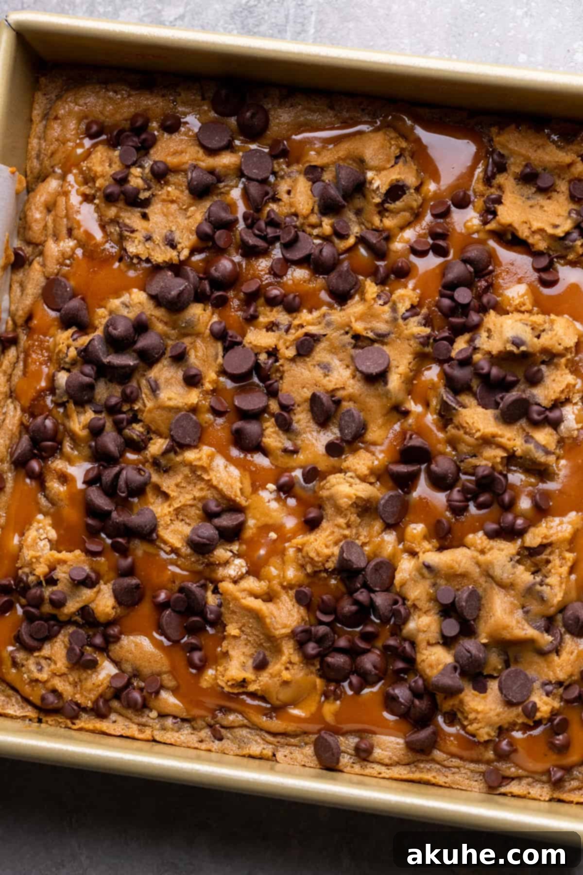Decadent Caramel Cookie Bars 9 Additional cookie dough dollops placed on top of the caramel layer, ready for final baking.