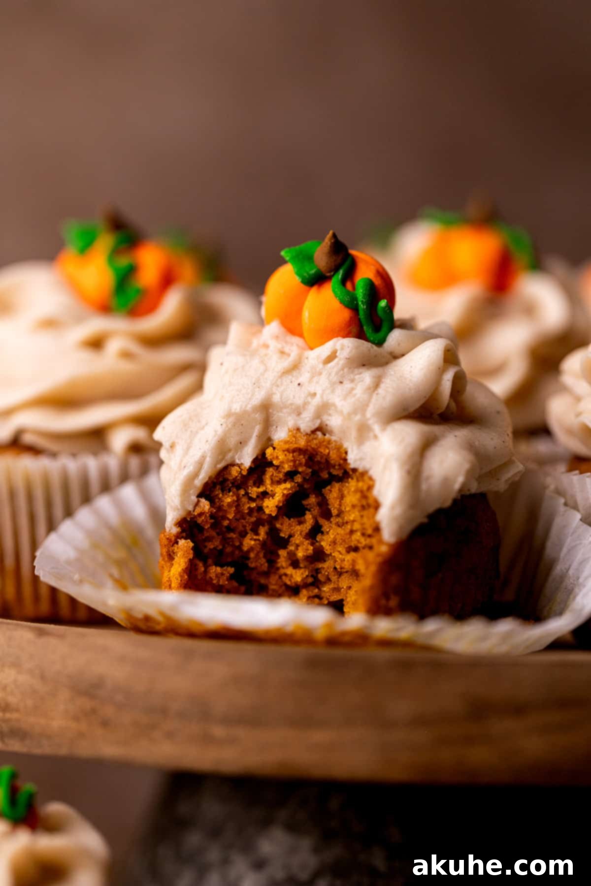 Autumn Pumpkin Spice Cupcakes 2 A perfectly baked, moist pumpkin cupcake with a bite taken out, showcasing the tender crumb and creamy cinnamon cream cheese frosting.